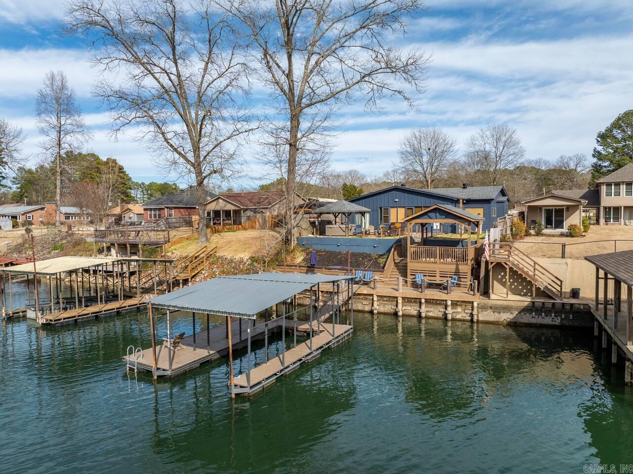 Experience the best of Lake Hamilton with this fully furnished, beautifully updated waterfront retreat that's equally perfect as your own lake home or a proven short-term rental investment. Featuring 4 king bedrooms, 2 full bathrooms with showers, and approximately 1,750 sq. ft., this home comfortably sleeps 10 with 4 king beds and 2 bunk beds, so no one gets stuck with the "small bed." Enjoy a private boat dock, hot tub, swim spa, grill, margarita machine, ice maker, and dedicated s'mores bar for unforgettable days and nights by the water. Major renovations and updates make this a true turnkey property. Located on the desirable river side of Lake Hamilton near Blakely Mountain Dam, you'll enjoy crystal-clear water ideal for boating, swimming, and fishing for trout, striped bass, and striper right from your private boardwalk. Whether you're searching for a weekend getaway, full-time lake home, or an investment with an active STR permit and proven rental history, this property is ready to enjoy from day one. Ample parking accommodates multiple vehicles and boat trailers. Schedule your showing today before it's gone! (Active STR. Do not disturb guests.)