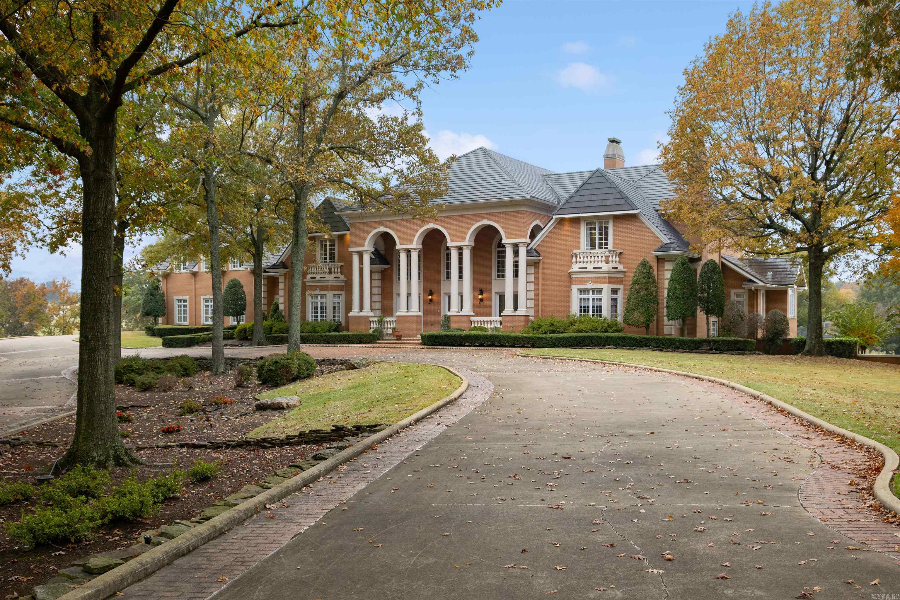 Built to impress yet designed to feel like home, this Ridgepointe estate is one of the largest and most remarkable residences in Arkansas. Spanning over 20,000 sqft on 4.5± acres overlooking the golf course, it offers unmatched space, craftsmanship, and value. The grand entry with dual staircases sets the tone for the elegance within, leading to a soaring two-story living room featuring an antique fireplace with a tall mirror above and stunning coffered ceilings. The main level includes a refined study, elevator, and a luxurious primary suite with sitting area, wet bar, dual closets, and a spa-inspired bath. Entertain in the sunroom, screened lanai, or the impressive lower level with bar, gym, steam shower, sauna, and office. Upstairs, a private apartment offers its own kitchen, dining, and living area. With 7 bedrooms, library, 8 full and 2 half baths, safe room, and a 5-car garage plus RV garage, this estate defines luxury living.