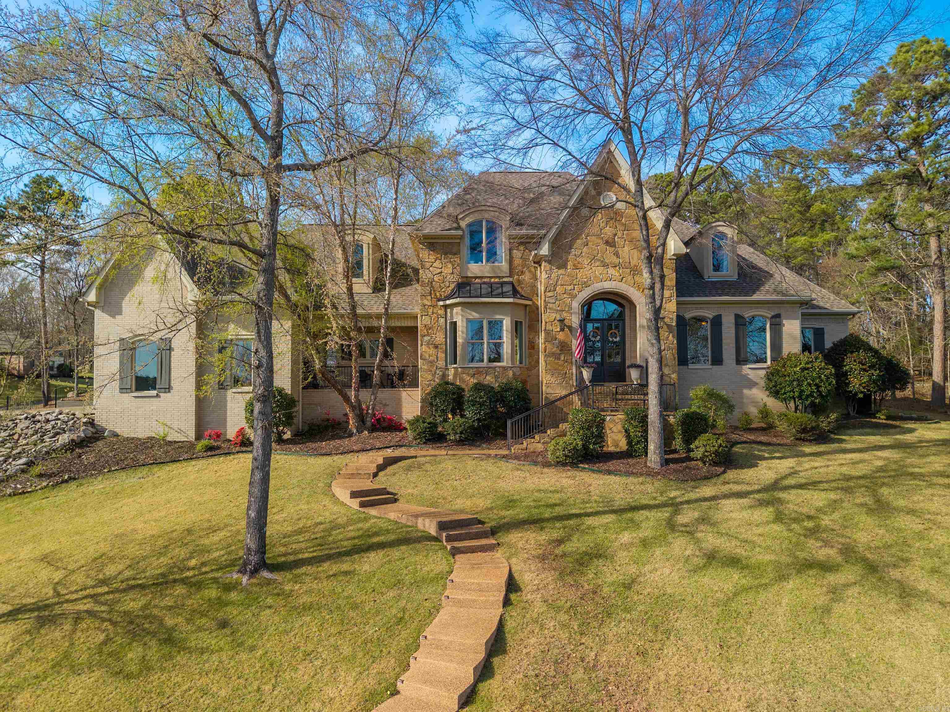Welcome to the highly sought-after Red Oak Ridge, Hot Springs premier gated community. Nestled in a natural oasis surrounded by trees, this beautifully custom-built, updated home features a front balcony perfectly positioned for stunning Red Oak Lake views. The freshly painted, versatile floor plan offers 4 bedrooms, 3.5 baths, and an office used as a 5th bedroom. A mudroom with removable cubbies provides a perfect drop zone. The extra-large, fully remodeled chef’s kitchen boasts endless storage, a walk-in pantry, gorgeous new countertops, instant hot water, and premium appliances, including a WiFi Café double oven and 6-burner gas cooktop. Entertain in spacious living areas with updated lighting and two fireplaces featuring sleek new tile. The primary suite is a private retreat with new hardwood floors and spacious his-and-hers closets with added upper storage. Upstairs features 3 bedrooms with walk-in closets, 2 full baths (one with new tile), a new linen closet, upgraded insulation, and brand-new carpet. Complete with a freshly painted front door and shutters, a garden bed, and a garage with extensive built-in shelving, this pristine property is a must-see.