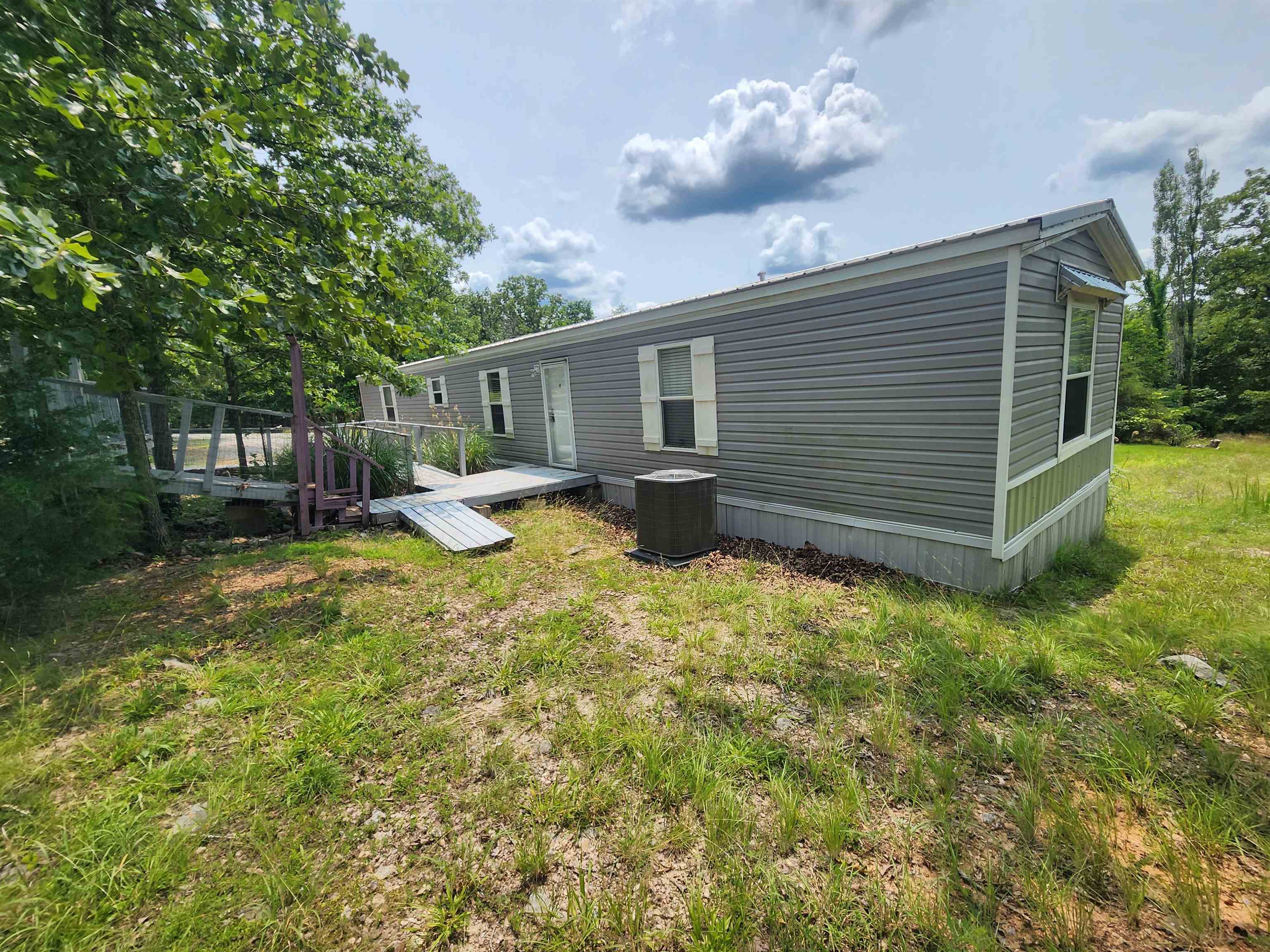 7 +/- acres M/L Beautifully landscaped with 2 mobile homes, the newer of the 2 is a 2019 3 bedroom/ 2-bathroom home (see virtual tour) with open floor plan in the kitchen dining and living room area. Very well maintained, with new carport and flooring installed. The 2nd mobile home could be used for an in-law suite, overflow guests or just a storage place, as it is now. The 2nd home could use some updating and a little TLC. It is a 2 bed, 1 bath with very good bones. There is a 30 x 30 metal barn building with roll up doors on the front and back along with an attached 20 x 17 covered parking area. The walking trails through out the front half of the property are lined with stones and gorgeous landscaping. There are some benches along the trails to sit and enjoy the sound of nature. The woods on the back half of the property would be ideal for hunters or nature lovers just looking to get deeper with nature. New chat stone driveway and parking pads. Make an appointment to see this property and come get your slice of Ozarks foothills living. This home is not eligible for VA, FHA or USDA-RD.