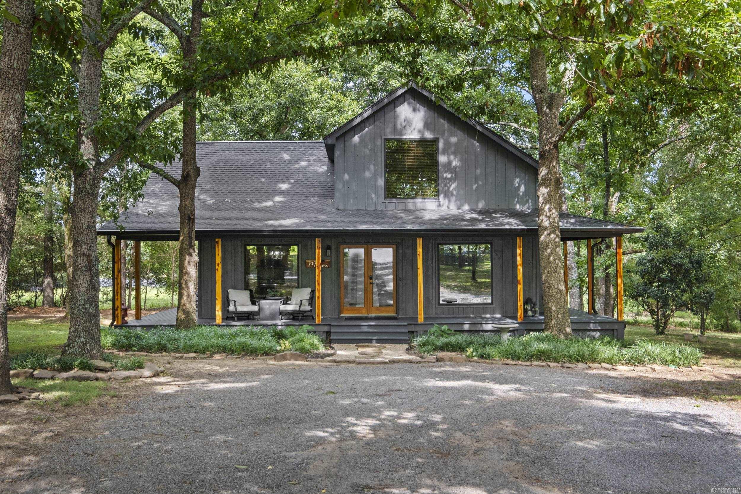 Nestled on 1.23 wooded acres, this beautifully updated 2-bedroom, 2-bath home offers the perfect blend of privacy and convenience. Tucked among mature trees, you'll enjoy the peaceful feeling of being secluded while remaining just minutes from shopping, dining, and everyday amenities. The inviting wraparound porch welcomes you home and provides the perfect spot to relax and enjoy the surrounding nature. Inside, you'll find a warm, open living space filled with natural light, modern finishes, and rustic charm. The spacious layout offers comfortable living with two well-appointed bedrooms and two full bathrooms. Whether you're looking for a full-time residence, weekend getaway, or investment opportunity, this property offers the tranquility of country living without sacrificing access to town. Don't miss this unique retreat where comfort, character, and location come together.