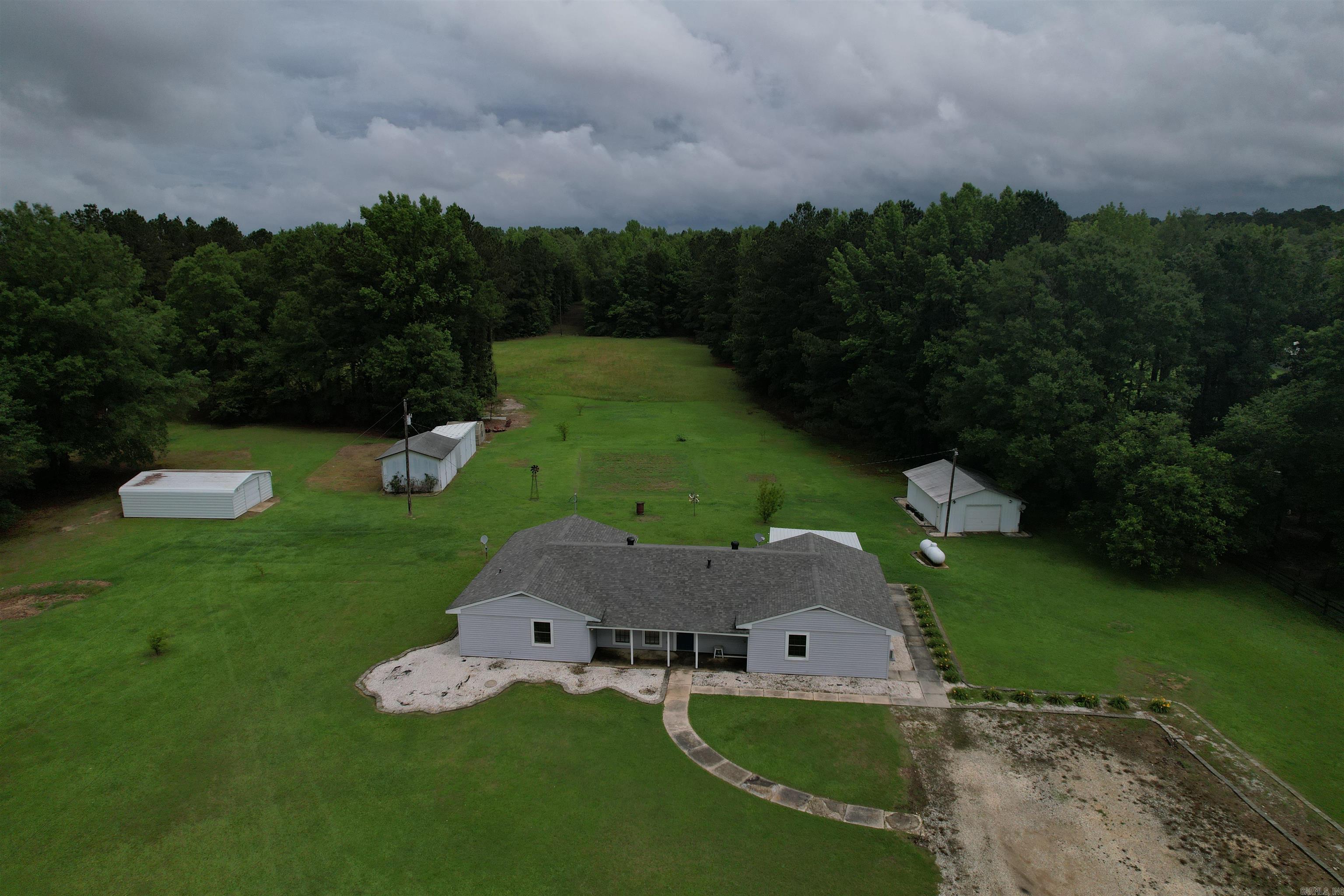 Discover this 4-bedroom, 3.5-bathroom home on 10 acres. It includes a workshop, detached garage, 2 tractor sheds, and a greenhouse. The ORIGINAL OWNER has kept it in great shape, and has replaced the roof, HVAC, and water heater within the last six years. The primary suite has a full bathroom and walk-in closet. All bedrooms have new carpet. The living room, dining room, and kitchen are large and welcoming. There's a den (or bonus space) that steps out to a cedar, screened patio. The laundry room has a sink and a half bath. The garage is now a bonus room with a full bath and new mini-split, ideal for a man cave or game room. The property has a secondary septic system for another house. The greenhouse and detached garage have electricity, water, and climate control. The workshop has electricity. Exterior cameras provide added security convey. This home is comfortable and functional, ready for you!