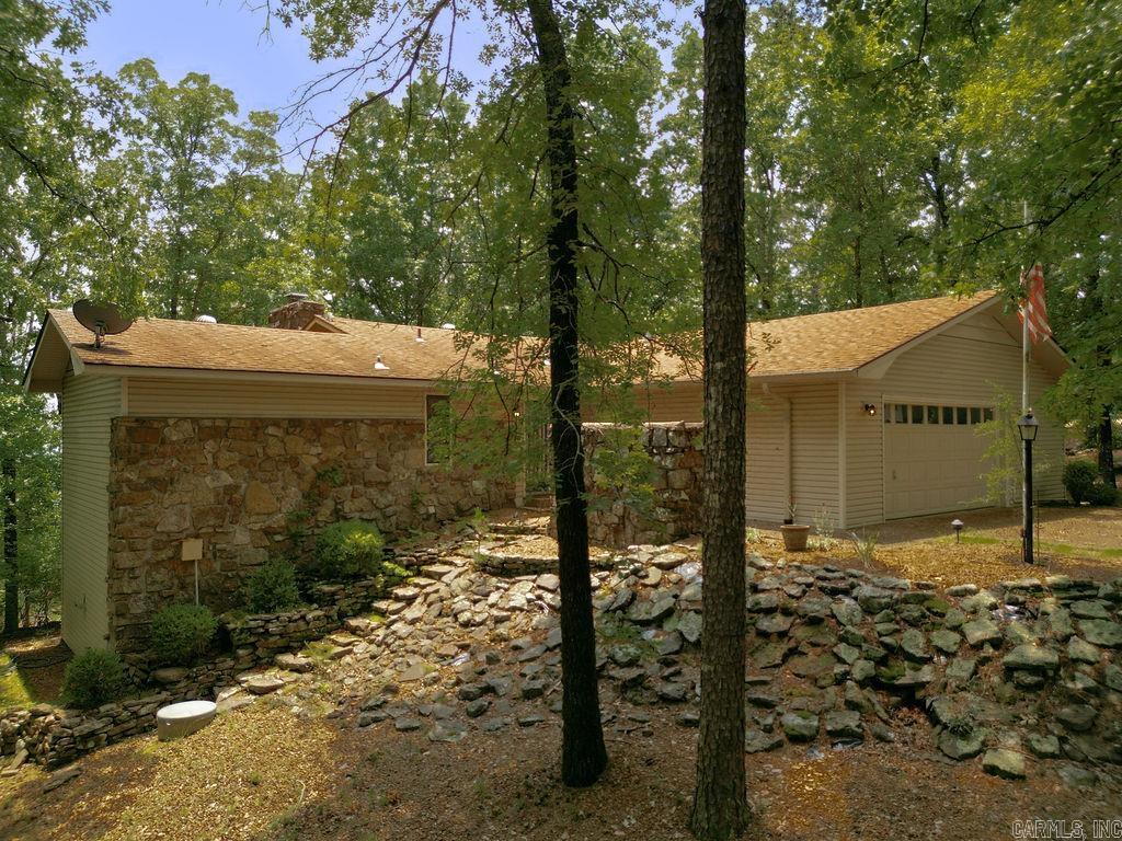Experience lake living in this Greers Ferry Lake view home in Fairfield Bay, AR. This inviting property features a vaulted living area with wood beam ceilings and easy access to a spacious deck offering scenic views. The dining area includes built-in glass cabinets and opens to a large kitchen with island. The main level offers a primary suite with tray ceiling and en suite bath featuring a walk-in tub and separate shower, along with a sunroom, half bath, and laundry. The lower level includes an oversized screened-in deck, family room with stone fireplace and bookshelves, two bedrooms, a full bath, bonus room, and storage. Upgrades include a new water heater and stove, and two propane tanks, one dedicated to the fireplace.  With proximity to the amenities the community provides, including 2 golf courses, 3 swimming pools, pickleball & tennis courts, ATV/UTV trails, a full-service marina & just moments away from the unspoiled Greers Ferry Lake, this is an opportunity in the Ozarks not to be overlooked. Be sure and visit the virtual tour.  Some photos are virtually staged or enhanced using AI to re-image the space.