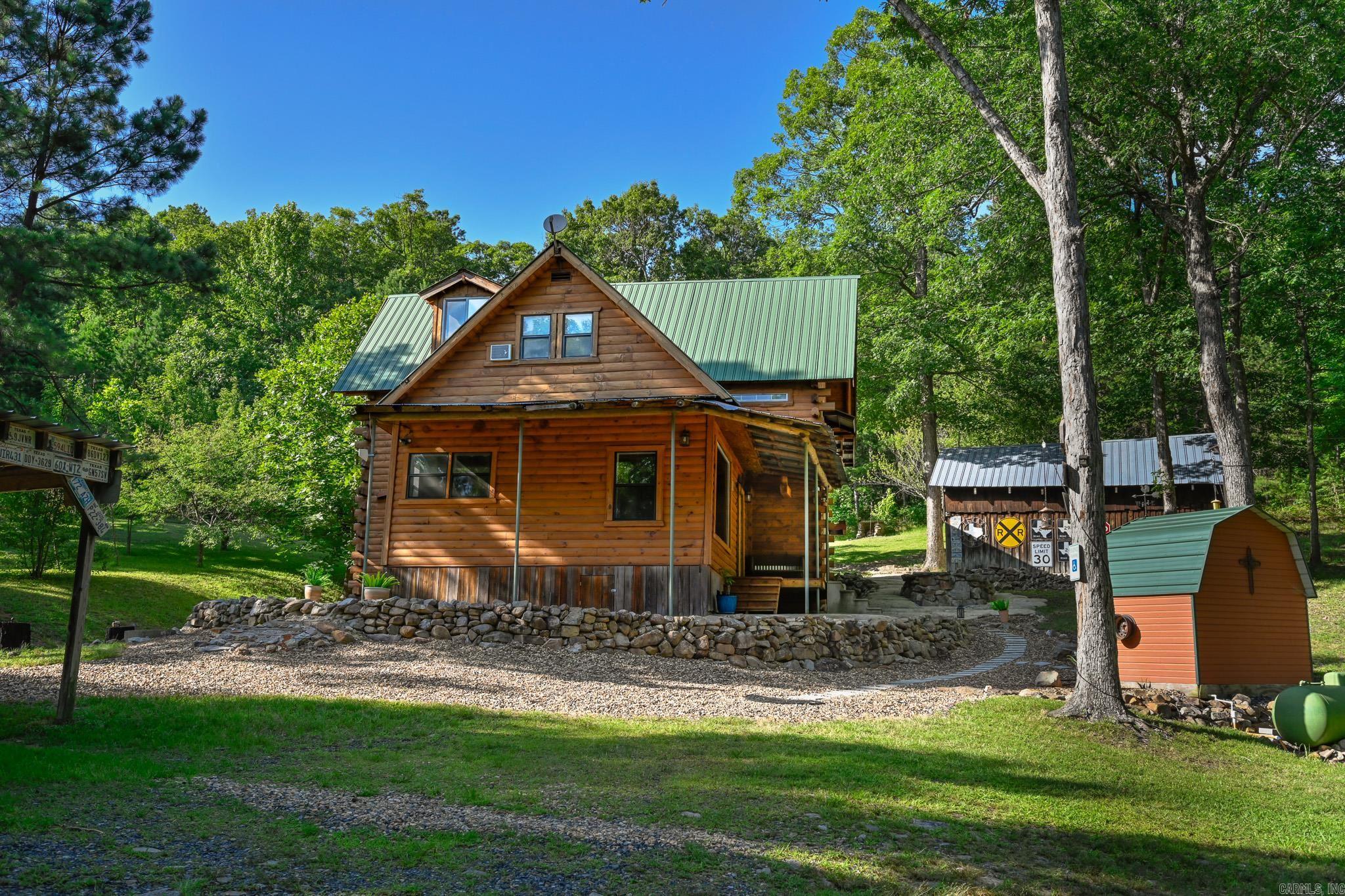Stunning log cabin retreat just 2.5 miles from the Bike Trails, and close to Queen Wilhelmina State Park and nestled in the Ouachita Mountains! This 3-bedroom, 3-bath home with an amazing loft offers the perfect blend of rustic charm and modern comfort. Natural log walls and staircase set the tone, while a one-of-a-kind walk-in shower built from rocks found on the property adds a truly unique touch. Mountain views, beautiful rock, and a handy workshop round out this incredible property. Extensively updated by the current owners: new mini split, whole-house generator, 2 propane tanks 250 and 500 gallon, reinforced crawl space, updated flooring and carpet, new deck wood and railing, covered parking for 4 vehicles, Anderson screen doors, and the entire home was professionally stripped, stained, and sealed. Recent additions include blown-in attic insulation, radiant barrier and auto vents in crawl space, and new master bath cabinets. Connectivity is a non-issue, Starlink and AT&T both work great, and sellers may transfer Starlink to new owners. Furnishings negotiable. Whether you’re looking for a vacation getaway or a permanent residence, this one is not to be missed!
