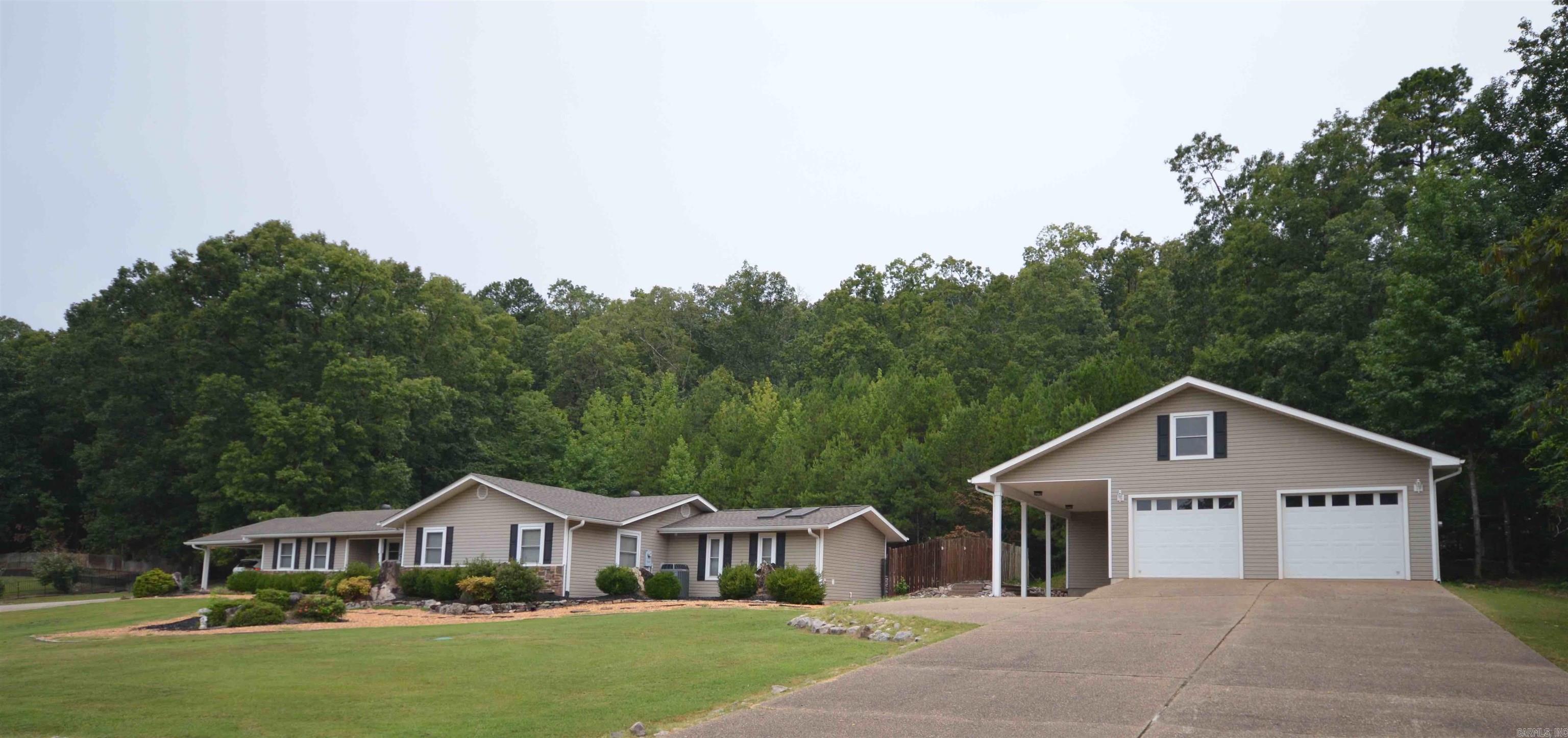 Nestled in a location with a road less traveled, this ranch-style home on 3+ acres off the beaten path is located outside of Hot Springs Village, so there's no POA and you're just 20 minutes to downtown Hot Springs, Bathhouse Row, Oaklawn Race Track and Casino and loads of shopping. The main bath has a luxury shower, built-in vanity, lots of storage and 4 skylights for extra light and stargazing. The main bedroom has a secure safe room with double locks. Mature landscaping, inground sports pool, outdoor kitchen in the gazebo and a spectacular view of evergreens and maples on the upslope are some of the many features this home offers, including a media room with propane gas log stove, pantry and newer appliances. Roof replaced in 2023. The 40 x 40 detached garage with double garage doors has been updated to include a full bathroom with tankless hot water heater and storage/workshop. Just outside the garage is a covered RV stall complete with a 50 Amp service, water access and an evacuation hookup. All this in a resort-like setting