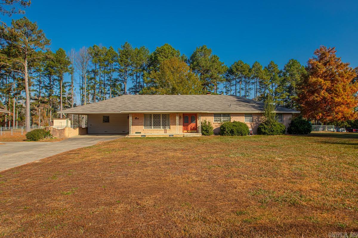 Lovely three-bedroom, two-bath home situated on 1.81 acres! This home features a bright sunroom, updated & shared bath with a new tiled shower, and the primary suite offering a walk-in tub for added comfort. Enjoy new vinyl plank flooring throughout, a gas-burning fireplace, and a kitchen equipped with granite countertops and a gas cookstove. Full-house generator is an added peace of mind.   The property includes a fenced backyard, a large laundry room, and excellent storage with a 28 × 40 two-bay detached garage/shop plus a double carport. One of the lots lies within the city limits, allowing access to city trash pickup, while the home itself operates on a septic system. Formal living and dining areas flow into the kitchen, breakfast area, and den—providing a great layout for everyday living and entertaining.  Home has full house generator.  Property is within an hours drive to Hot Springs National Park and Oaklawn. Some photos are digitally staged for reference of furniture. Agent see agent remarks prior to writing offer.