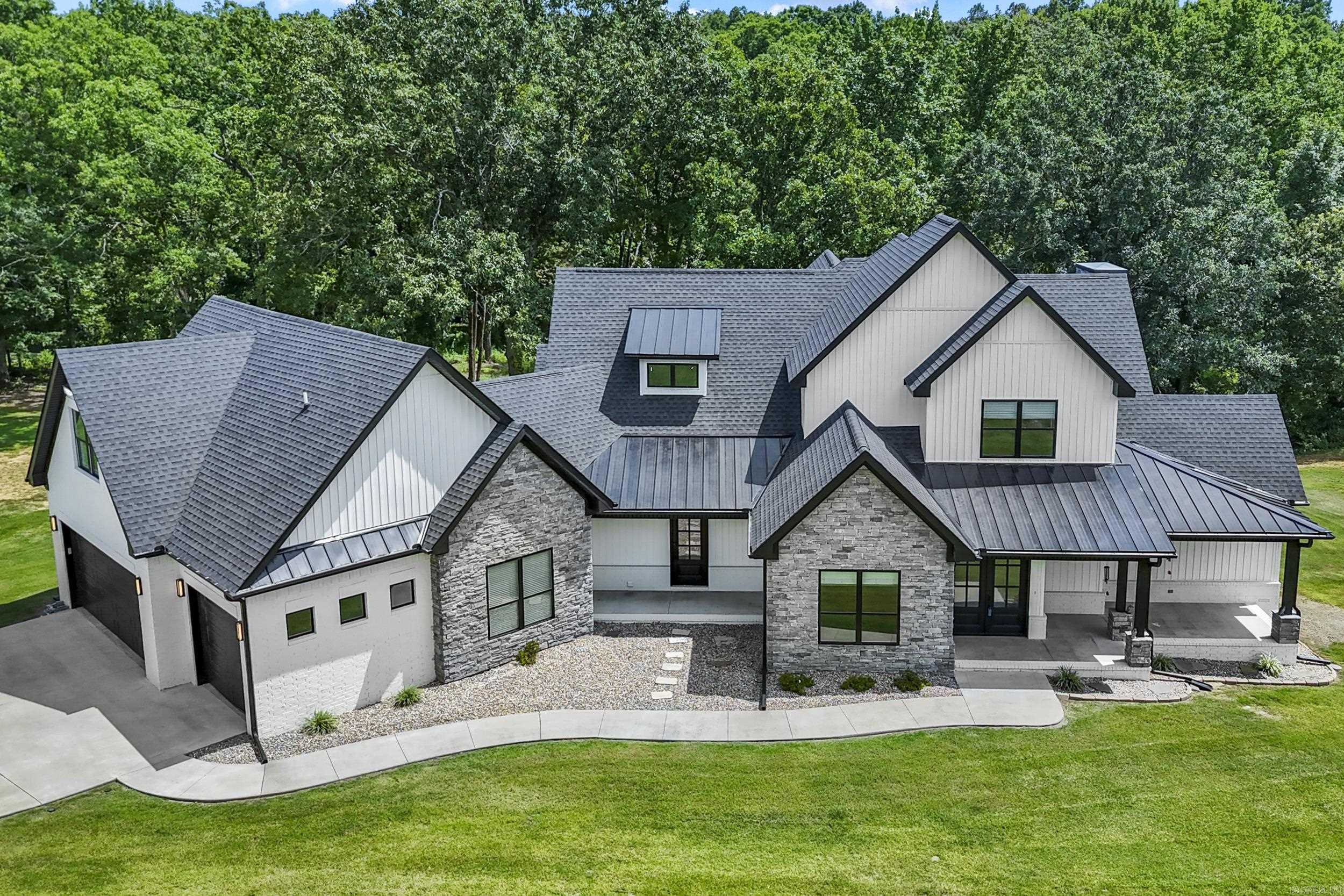 Wake up to peaceful lake views every day in this exceptional custom home on 2.64 acres in a prestigious gated community! Built in 2024, this stunning 4,291 SF home features an open floor plan filled with natural light from a wall of windows overlooking the neighborhood fishing lake. The vaulted great room showcases exposed wood beams and a floor-to-ceiling stone fireplace. The chef's kitchen offers a massive island, breakfast bar, gas cooktop, double wall ovens, built-in microwave, oversized walk-in pantry with butcher block countertops, beverage refrigerator and refrigerator that conveys. Luxurious main-level primary suite. Two laundry rooms with stackable washer/dryer conveying. Four full baths with flexible space that could serve as a 5th bedroom. Relax on the oversized covered patio with a wood ceiling and lake views. Oversized 3-car garage with a 278 SF heated/cooled dog room and plumbing for a future dog wash. Spray foam insulation, radiant barrier roof decking, tankless water heater, LVP flooring, no carpet. Located in Cabot School District.
