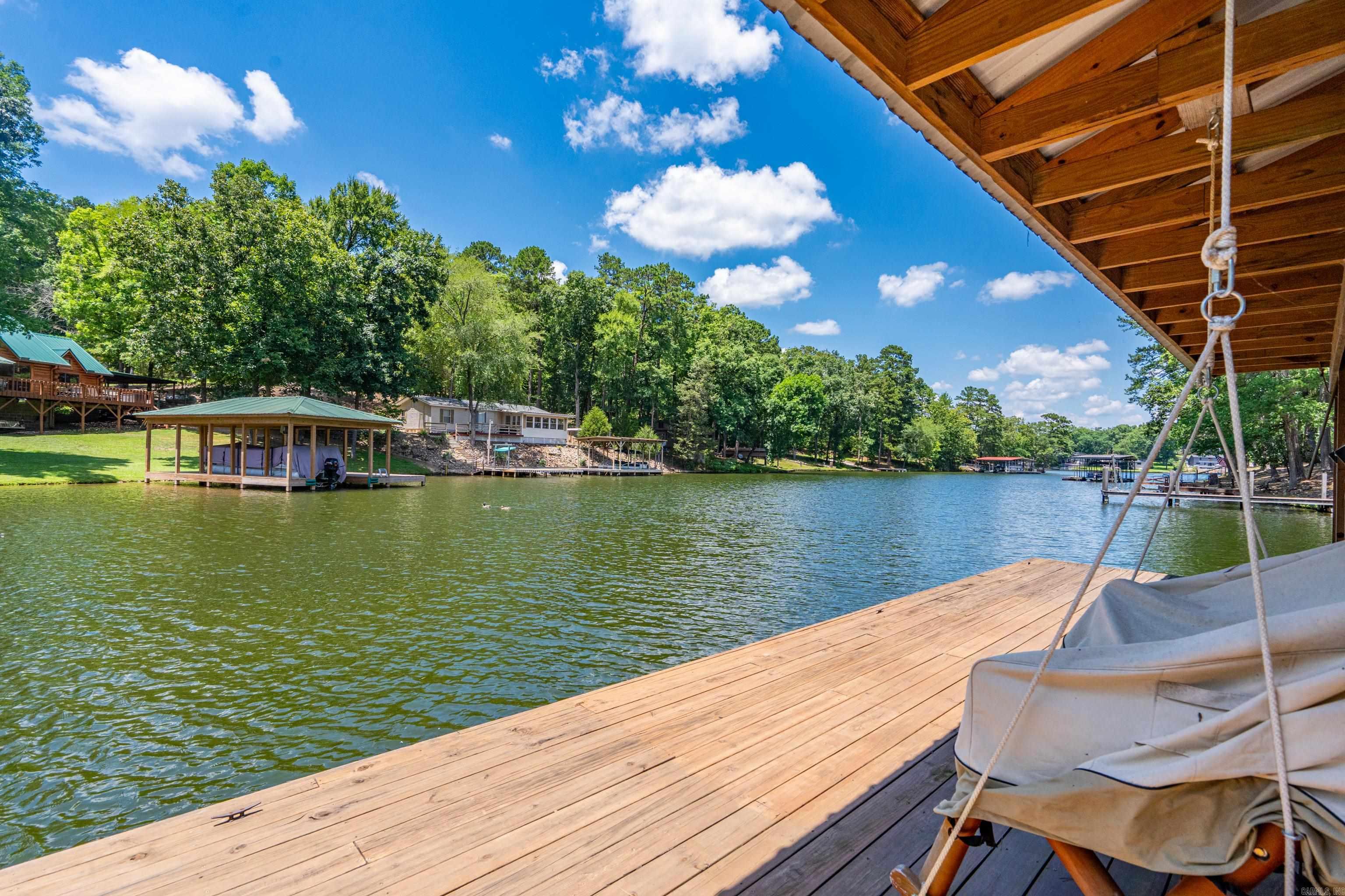 Welcome to the lake life you've been dreaming about! This spacious all brick home was built for entertaining, relaxing, and making memories. With a RARE private boat ramp (these are not common), boat dock, a gorgeous lakefront lot, you'll spend less time loading up & more time enjoying Lake Hamilton-tubing, island adventures & restaurants & more! The expansive back deck offers breathtaking lake views. Over 100 ft lake frontage! perfect spot for sunset gatherings  Whether you're hosting family reunions, holiday celebrations, or weekend lake parties, there's room for everyone here!  The lower level is a standout feature, offering a huge living area, large bedroom, full bathroom, and its own private exterior entrance—making it ideal for guests, extended family, a mother-in-law suite, or even additional rental potential.  Located in the county, this property offers the flexibility many buyers are looking for, including the possibility of short-term rentals. Rare lake amenities, incredible views, privacy, wildlife, and plenty of space to spread out—this is more than a home; it's a waterfront lifestyle waiting to be enjoyed. Don't let this one sail away!
