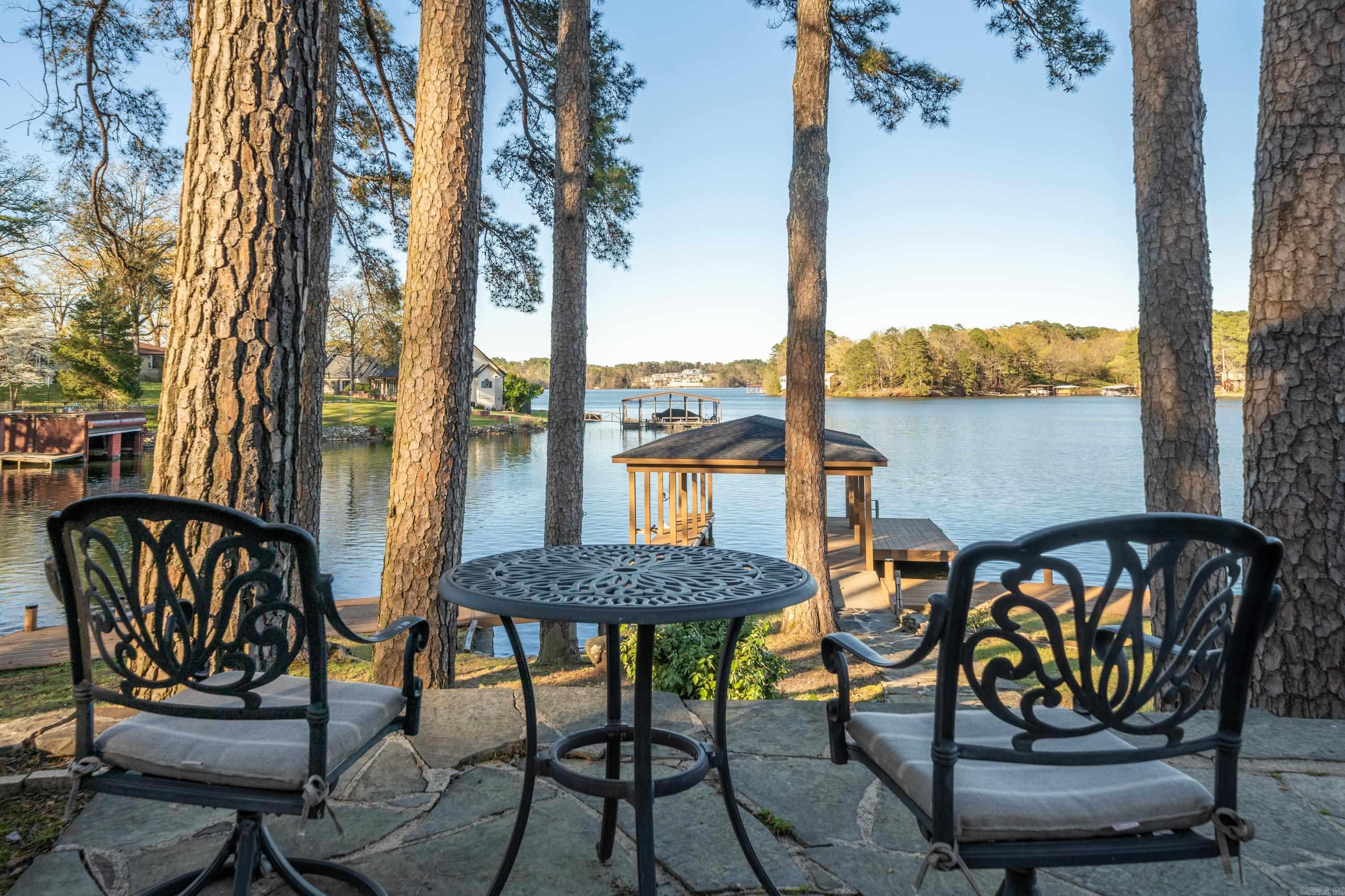 PRICED TO SELL!! This enchanting stone and cypress home offers an unparalleled setting for unforgettable family gatherings and lakeside adventures. Nestled on 100 feet of Lake Hamilton frontage in a quiet neighborhood off Hwy 7 in Hot Springs, it provides breathtaking main channel lake views with year-round water access.  As you step inside, a grand library welcomes you with its updated open floor plan and expansive windows framing the tranquil lake view. The chef's kitchen is equipped with top-of-the-line appliances including a Sub Zero refrigerator, Viking gas stove, and a large custom-built pantry, making it a delightful space for culinary creations.  Retreat to the primary suite featuring vaulted ceilings, a luxurious bathroom with views of the lake, and a private balcony, perfect for relaxing evenings. The home also boasts a private guest suite with a separate entrance from the main house, ensuring privacy and comfort for visitors.  Additional features include an oversized laundry room, plenty of storage closets, refinished hardwood floors, new windows, and shingles replaced in 2023. With a boat dock featuring a swim platform and a jet ski lift offers endless opportunities.