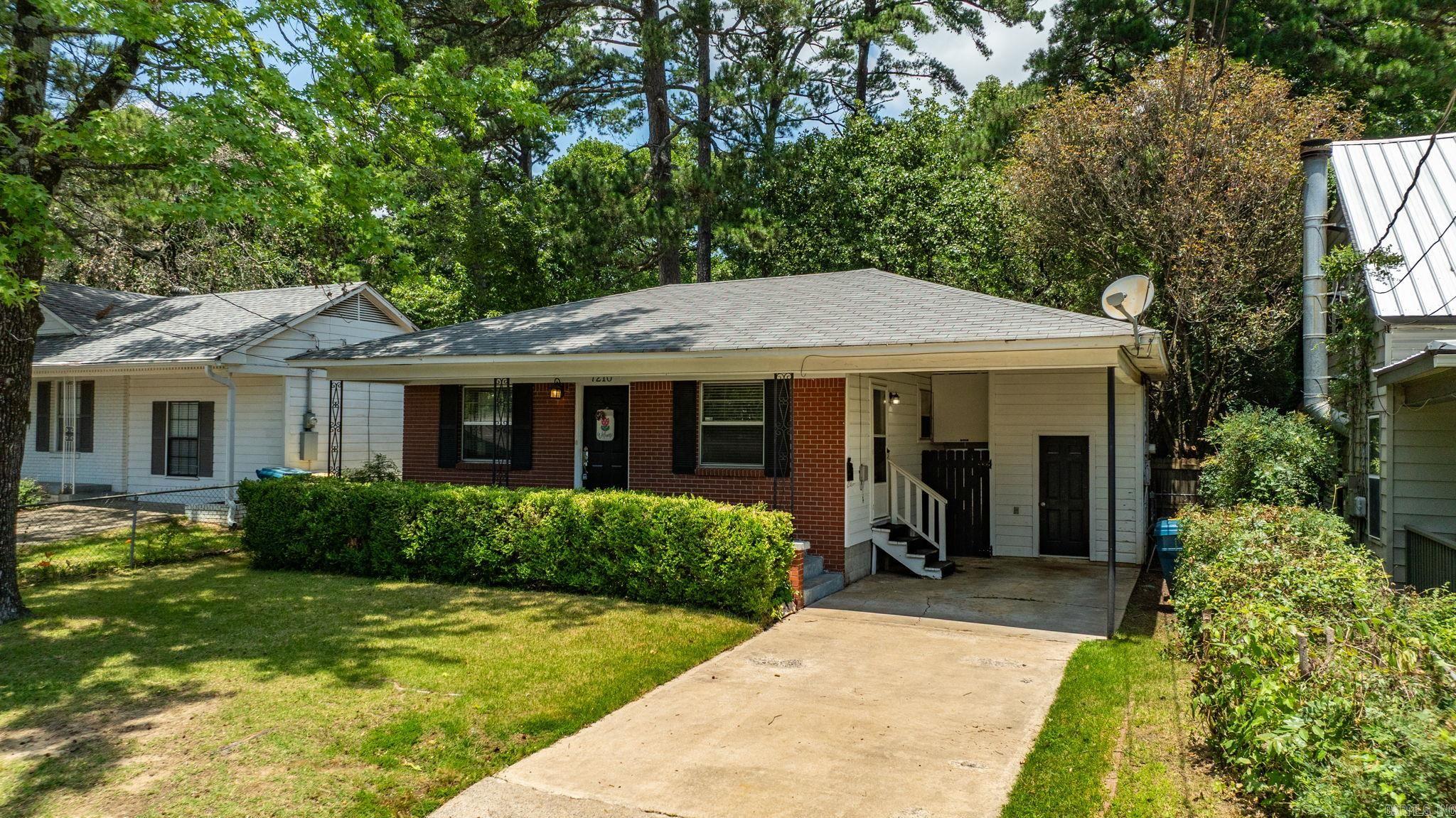 Charming brick ranch in an established Central Arkansas neighborhood, offering the rare combination of original hardwood floors and a true open-concept layout—a feature you won't often find in homes of this era. The living room flows seamlessly into the dining area and breakfast-bar kitchen, creating a bright, connected space perfect for everyday living and entertaining. The kitchen features stainless steel appliances, including a gas range, abundant white cabinetry, and a peninsula with bar seating that opens directly to the main living space. Two comfortable bedrooms offer generous closet space, gleaming hardwood floors, and natural light throughout. The full bath includes a tub/shower combination and updated vanity. Out back, enjoy a covered porch with a ceiling fan overlooking a spacious, fully fenced, tree-shaded yard—ideal for relaxing, grilling, and pets. A one-car carport and additional storage shed complete the package. Mature shade trees and timeless curb appeal round out this move-in-ready home. Don't miss your chance to own a home with character, original details, and a layout ahead of its time.