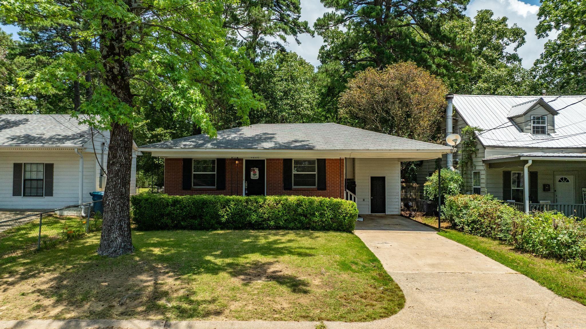 Charming brick ranch in an established Central Arkansas neighborhood, offering the rare combination of original hardwood floors and a true open-concept layout—a feature you won't often find in homes of this era. The living room flows seamlessly into the dining area and breakfast-bar kitchen, creating a bright, connected space perfect for everyday living and entertaining. The kitchen features stainless steel appliances, including a gas range, abundant white cabinetry, and a peninsula with bar seating that opens directly to the main living space. Two comfortable bedrooms offer generous closet space, gleaming hardwood floors, and natural light throughout. The full bath includes a tub/shower combination and updated vanity. Out back, enjoy a covered porch with a ceiling fan overlooking a spacious, fully fenced, tree-shaded yard—ideal for relaxing, grilling, and pets. A one-car carport and additional storage shed complete the package. Mature shade trees and timeless curb appeal round out this move-in-ready home. Don't miss your chance to own a home with character, original details, and a layout ahead of its time.