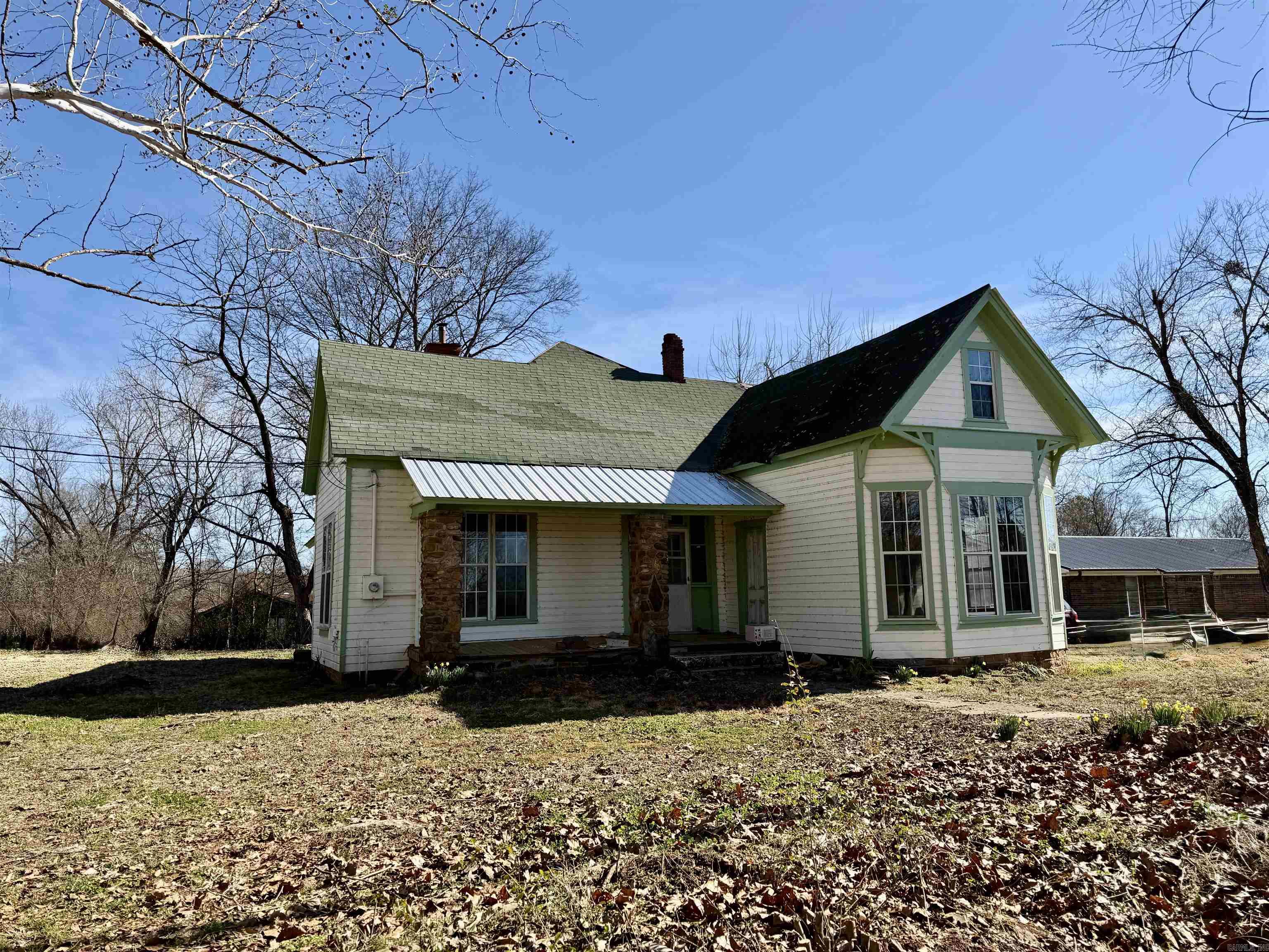 Victorian fixer-upper opportunity on a spacious corner lot in Lamar, full of character and original charm. From the hardwood flooring to the trim, moldings, and doors, many historic features remain intact and ready to be restored to their former beauty. The upper level offers three bedrooms and a bathroom, while the main floor includes a formal dining room, laundry area, and two additional bedrooms—one of which could easily serve as a den or office.  Rich woodwork throughout, fresh exterior paint, and included shingles add value to this restoration project. Recent improvements include newly roughed-in plumbing and electrical systems, giving you a strong head start toward completion. A rare chance to transform a classic Victorian into something truly special.