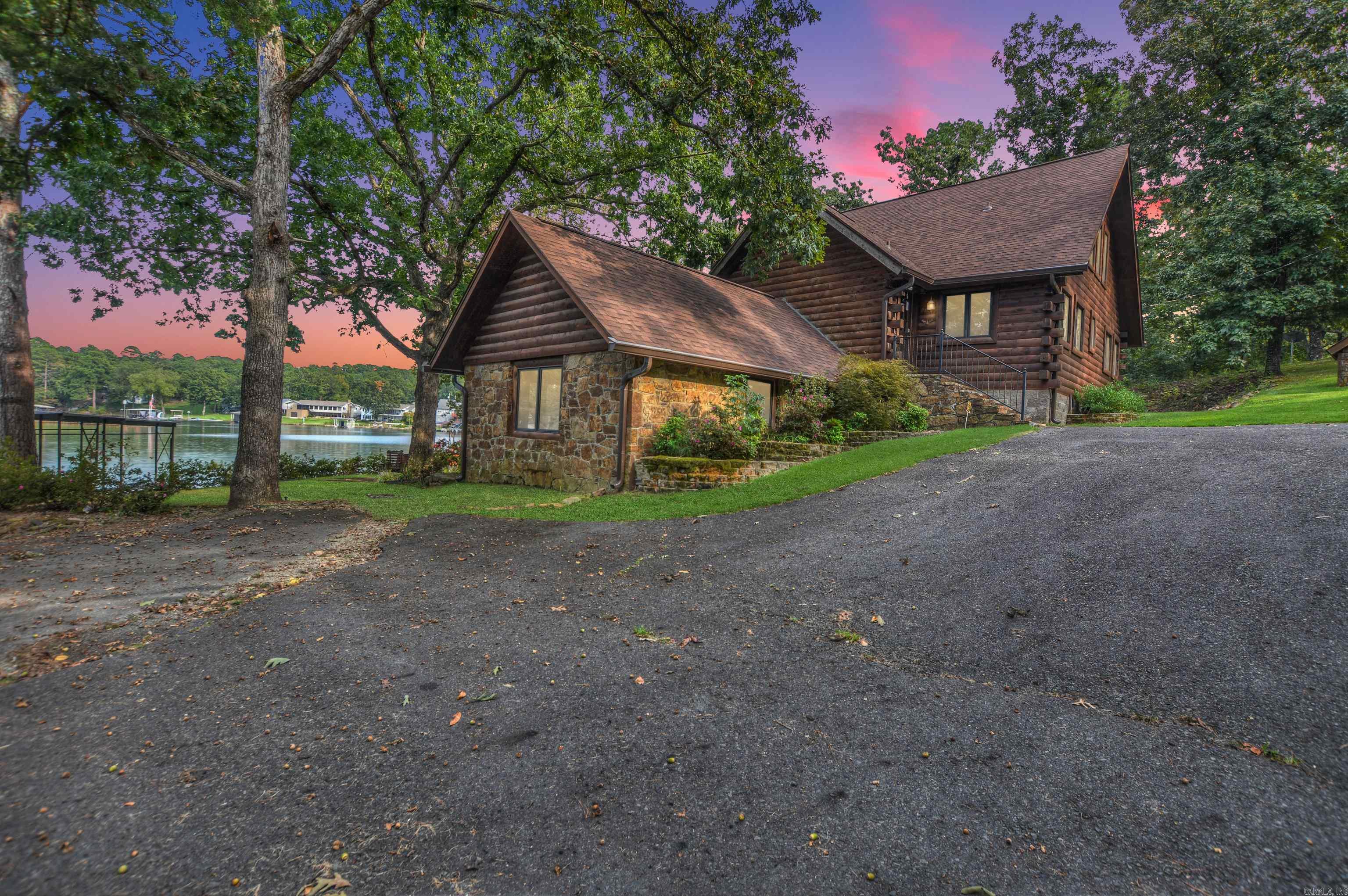 Lake Hamilton waterfront retreat! This 3,264 sq. ft., 3-story log cabin offers 149’ of shoreline with stone seawall, private boat ramp, covered double boat dock, and separate swim dock. Built in 2002 on a 1.8-acre treed lot with circle drive and detached workshop, it’s ideal as a primary residence, getaway, or nightly rental (no restrictions). The walk-out lower level features a game room, family room, kitchenette, bedroom, bath & laundry. Main level has 2 bedrooms, bath, open kitchen, family room with cozy stove, and walls of glass opening to an expansive deck. Upper level offers a private suite with bedroom, bath, and dual walk-in closets. Hardwood & tile floors plus walls of glass throughout. Proven rental history—move-in ready for lake living or investment!