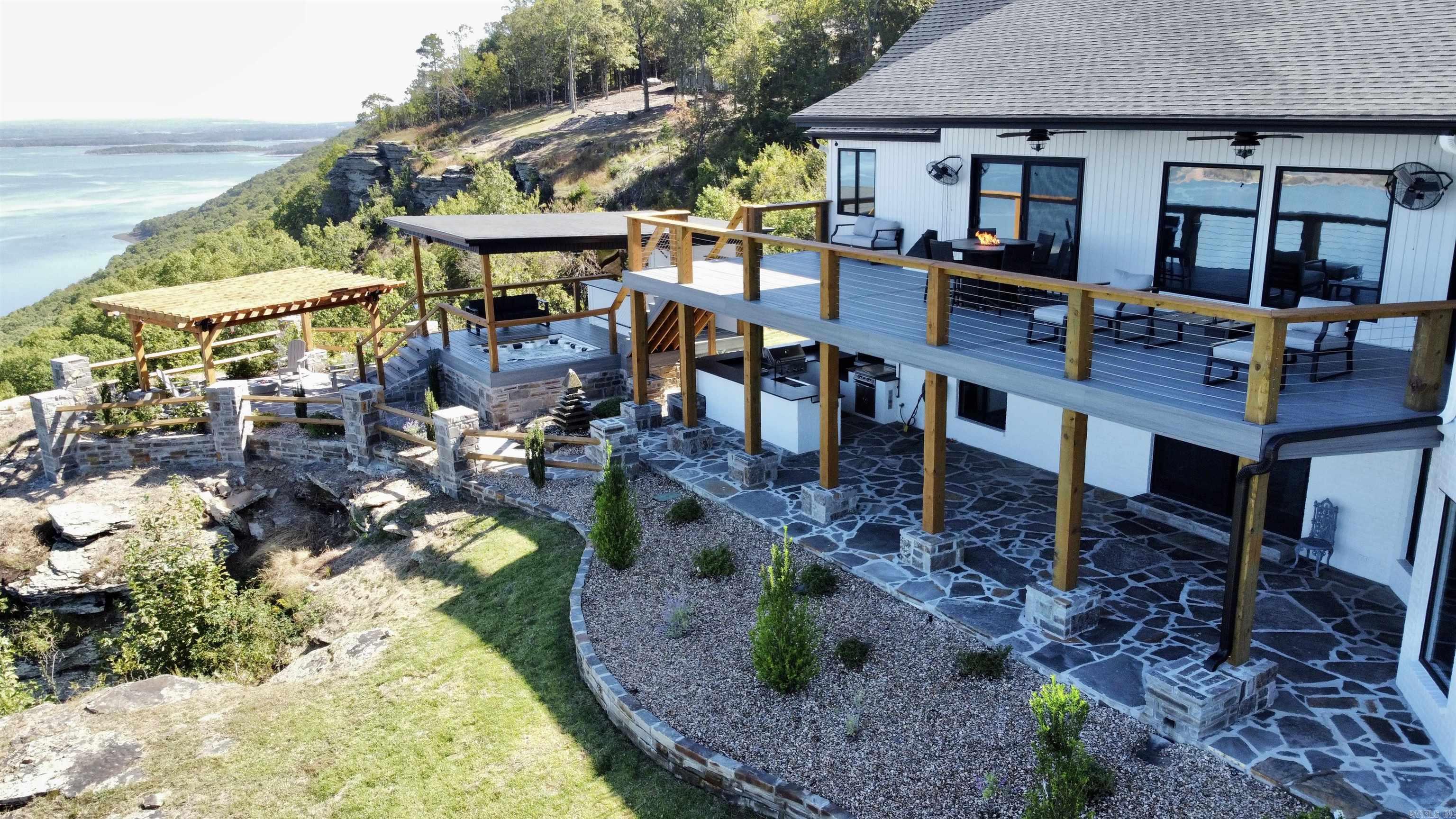 Fully Furnished. Perched high above Greers Ferry Lake, this stunning mountain-top retreat offers panoramic lake and Ozark views, luxury amenities, and turnkey convenience. Located near Quitman, the 4,404 SF home features 3 bedrooms, a sleeping den, 2 full baths, and 2 half baths. Designed for comfort and entertaining, Sonos Sound System inside and outside, whole home Generator, it also includes dual living rooms, gas fireplaces, smart TVs, pool table, dedicated office, treadmill, elliptical, and upscale finishes throughout. The spacious primary suite offers a walk-in closet and relaxing soaker tub. Outside, enjoy expansive multi-level decks, private hot tub, two gas fire pits, outdoor kitchen, grill area, refrigerator, dining space, and seasonal outdoor shower. Sold completely furnished with furniture, décor, and entertainment areas included, making it move-in ready or ideal for immediate short-term rental use. Minutes to boat ramp and lake access with 2 Car Garage. Excellent vacation rental potential or perfect personal getaway. Just bring your suitcase—everything else is already here.