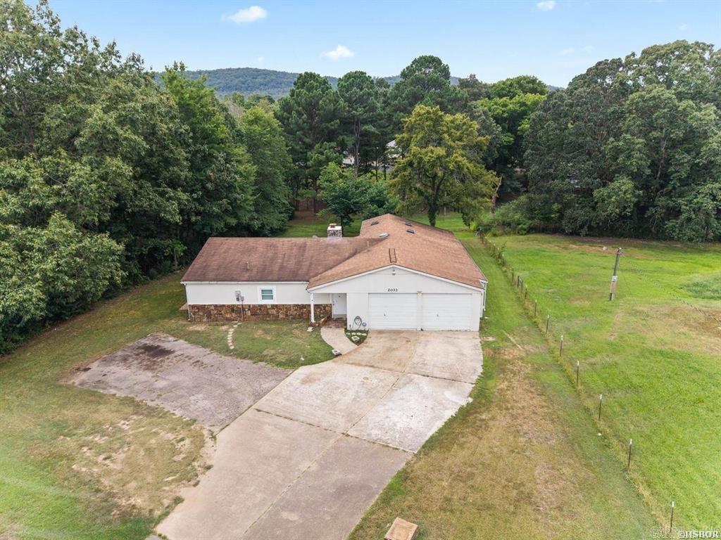 Welcome to this charming 2-bedroom, 2-bathroom home offering 1,318 square feet of comfortable living space on a generous 0.45-acre lot. Step inside to an inviting living room featuring vaulted ceilings, rich walnut paneling, and a floor-to-ceiling stone fireplace that creates the perfect focal point for relaxing or entertaining. Cozy up in the light-filled Arkansas Room, where wall-to-wall views overlook the peaceful, sprawling backyard setting. Hobbyists, mechanics, and craft lovers will fall in love with the massive 1,351-square-foot garage and workshop, providing endless possibilities for storage, projects, or vehicle storage. Situated in the desirable Fountain Lake School District, this exceptional property blends warmth, practical living space, and outstanding outdoor space -- Tons of potential on this one!!