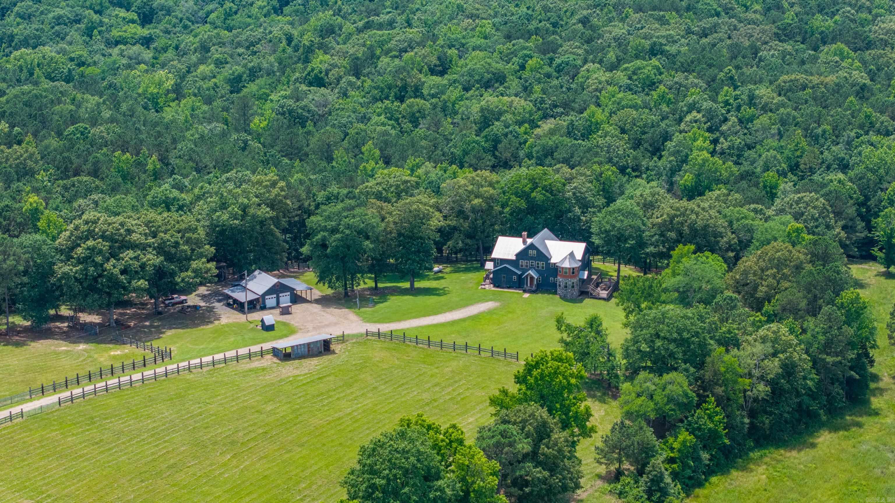 One-of-a-kind custom rustic retreat on 40 beautiful acres in Bismarck! This stunning two-story home offers over 3,800 square feet of living space, featuring rich natural materials throughout—including cypress, pine, oak, and antique logs—creating a warm, lodge-style atmosphere you won’t find anywhere else. Three master suites, soaring ceilings in the great room with a wrap-around catwalk overlooking  a  massive antique brick fireplace, and gorgeous wood flooring throughout, complemented by tile in the kitchen, baths and large laundry room. Tongue-and-groove pine ceilings and solid 6-inch insulated walls provide both character and efficiency. Enjoy the outdoors from the expansive 1300 sf of wraparound decking, with a portion covered for year-round relaxation. The 40-acre corner tract offers excellent access and a perfect mix of pasture and mature timber, including established pines and oaks. Inside, you’ll find a large game room complete with pool table, plus a unique two-story turret, and custom kitchen with antique wood cabinetry and a cook's fireplace. A detached garage/shop includes multiple covered areas ideal for tractors, ATVs, and equipment. Most furnishings convey.