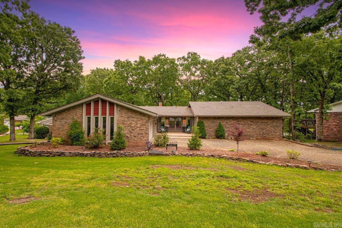 This is an opportunity to own your own slice of heaven! Nestled in the quiet Indian Hills neighborhood on the lake, this home offers cozy nights by the stacked rock fireplace, sunsets from the screened in porch, fishing from your backyard, morning walks around the neighborhood and so many memories for your family. This home features original hardwood floors, 2021 roof with covered gutters, sprinkler system, updated kitchen and baths, light fixtures, and exterior holiday lighting! Do not miss the large storage room under the house!