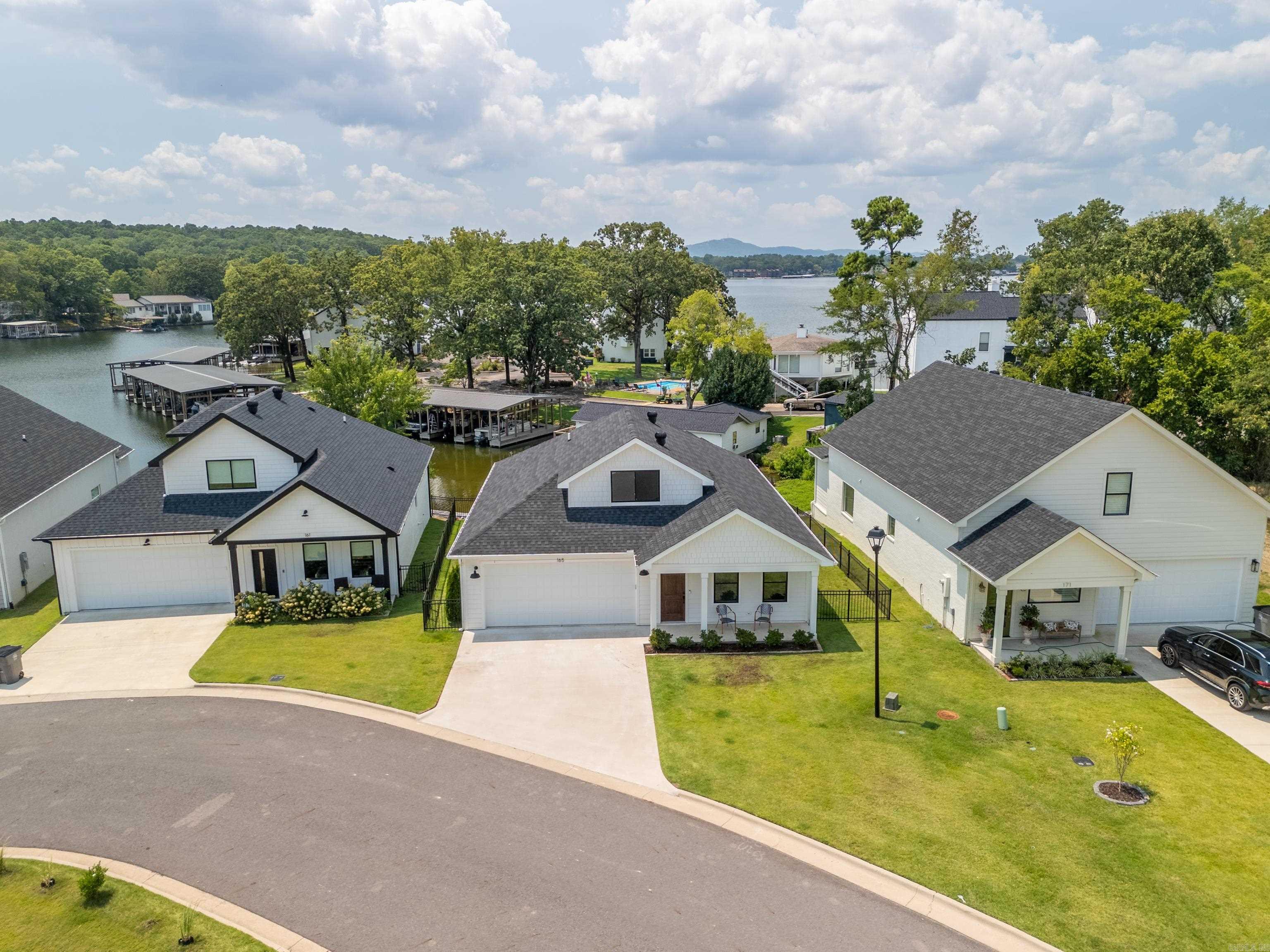 Enjoy lakefront living in this beautiful 2022 built home tucked in a quiet cove on Lake Hamilton. Enjoy effortless main-level living with a no step entry and open, light filled floor plan. Designer details shine throughout--from elegant lighting and custom drapes to premium LVP flooring. The main level primary suite includes a custom tile shower, walk in closets, and private deck access with stunning lake views. Upstairs offers two guest bedrooms and a full bath. Outdoor living shines with a lakeside deck, fenced yard, and a boardwalk to the water. Located in a private gated subdivision with a 2 car garage and just minutes from Hot Springs amenities-this is a lakefront living at its best!