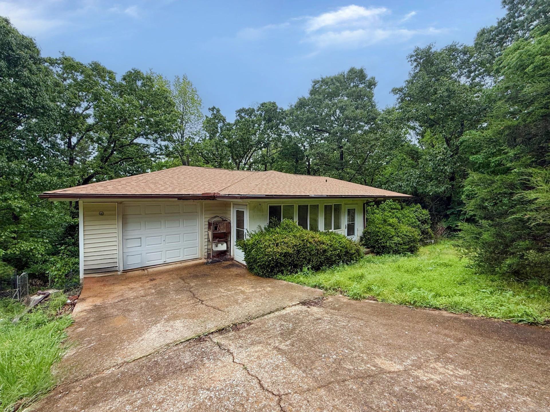 This home sits on a large lot and a functional single-level layout that offers significant potential for the right buyer.   This two-bedroom, two-bathroom home requires renovation but offers solid investment potential. The attached garage provides covered parking, while the existing deck creates outdoor space ready for restoration. Comprehensive updates will be needed throughout to realize the property's value.   Located on a private wooded lot between Lake Paradise and Lake Omaha, the property sits near Cherokee Village South Golf Course. The forested setting delivers seasonal foliage panorama views and clear starry night sky vistas from this secluded position.   The property needs significant work throughout, creating an opportunity for complete transformation while capitalizing on the dual lake access and natural privacy that the wooded lot provides to future owners.   Call today to schedule your showing and evaluate this home's renovation potential and solid foundation for your next project.