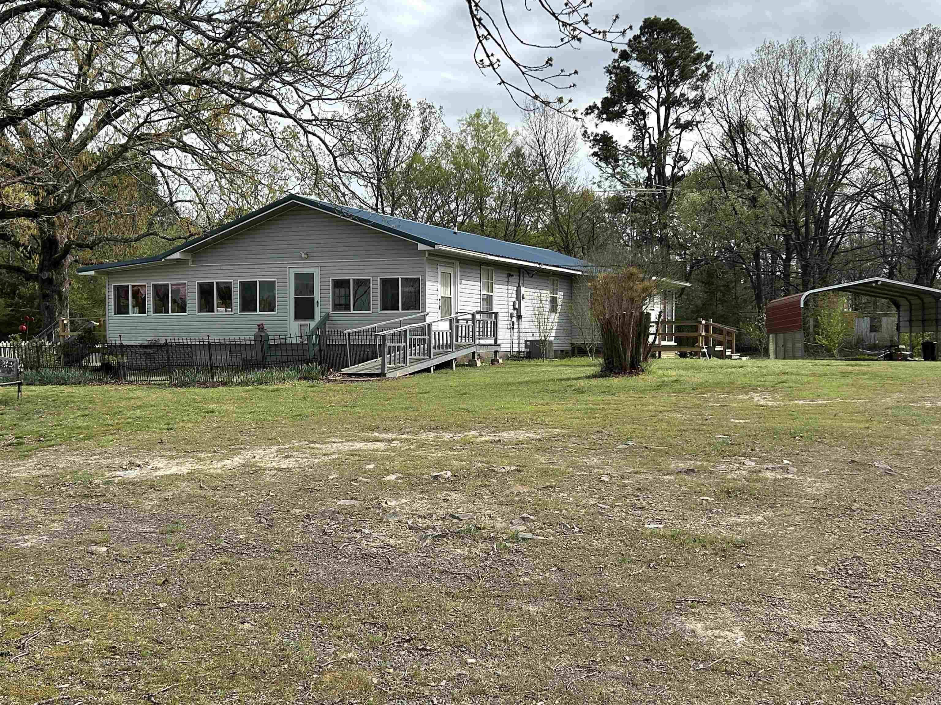 Charming rural setting featuring fruit trees and berry bushes, along with ample space for gardening! This spacious home includes 2 bedrooms (could easily be 3), 2 full bathrooms, laundry area and a bonus room suitable for an office or craft room. It also boasts 2 enclosed porches, multiple sheds, and 2 large carports. House has whole house attic fan!!   The house is positioned on a .65-acre lot.  One shed is insulated and has heat pump - heats and cools. The kitchen is equipped with 2 sinks, abundant counter space, and plenty of cabinets, along with a small movable island. There is a fenced area for pets and existing doggie doors. The property features a new metal roof installed in 2020 and a new HVAC system added in 2018, complemented by vinyl siding. Newly constructed porch steps provide access to each entrance, one with ramp.  Was built in 2000 by current owner, not in 1960 as tax record indicates. (there was an old cabin foundation when they bought it)  Fresh paint perhaps, otherwise move in ready!    This property is situated in a peaceful location, just 45 minutes from either Conway or Little Rock.  Seller including $6,000 for appliance & paint allowances or closing costs.