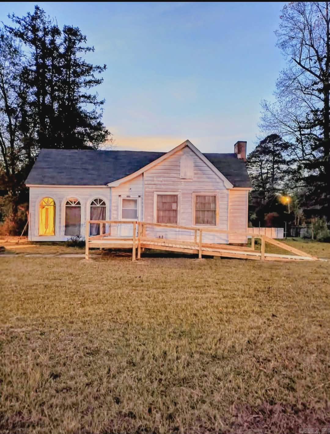 Located on approximately 1 acre offering opportunities for gardening, outdoor recreation, or additional improvements, this charming home offers a peaceful small-town setting with plenty of room to spread out. Originally built in 1938, the home carries classic character while providing the essentials for comfortable living. Inside, the home features hard wood flooring, cozy natural gas logs, central heat & air to keep the home comfortable year-round.  With plenty of space surrounding the home, the property provides a quiet rural atmosphere while still being within the community. This property blends historic character with rural space, making it appealing for buyers looking for a quiet setting, acreage within town limits, & the potential to update or personalize a classic Arkansas home. It has original glass door knobs, wood walls, inwall ironing board, new cinder block supports, new flooring, sub floor & toilet put in bathroom Spring 2025. This is a great house with huge rooms for a family moving to the area for work through the Direct Lithium Extraction (DLE) or college students at SAU.