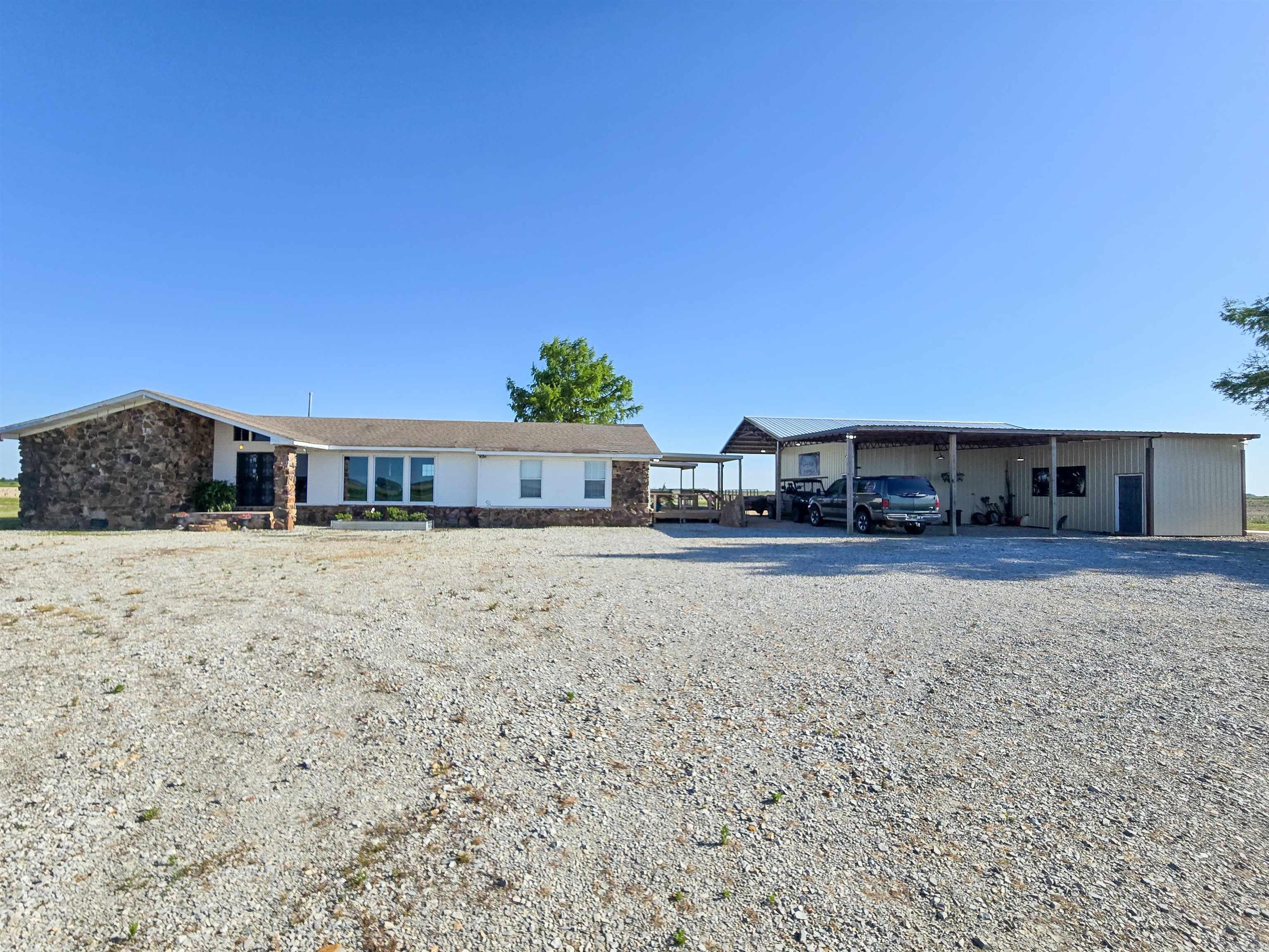 Experience the ultimate duck hunting retreat with this unique one-level stone & frame lodge on approximately 1 acre m/l along a paved road near some of the region’s best duck hunting. Designed for large groups, the property offers 4 spacious sleeping quarters with multiple bunk beds and full-size beds. The oversized living room features 3 picture windows for abundant natural light and opens to the spacious front entry with double doors. The large kitchen & dining area includes a U-shaped kitchen, solid surface breakfast bar with attached retro stools, solid wood island, pair of Whirlpool side-by-side refrigerator/freezers, electric range, micro-hood, Maxx Ice machine, commercial buffet warmer, stainless prep tables, BUNN commercial coffee brewer, plus dishes remaining. One bedroom includes a private bath with oversized custom tile shower, while the hall bath offers another oversized tile shower, bidet toilet & urinal. Covered west-side decks include a grilling porch. Also included is a 1320 sq. ft. shop with concrete flooring and attached 1080 sq. ft. L-shaped canopy. Designed for lodge-style accommodations, yet easily adaptable for traditional residential living.