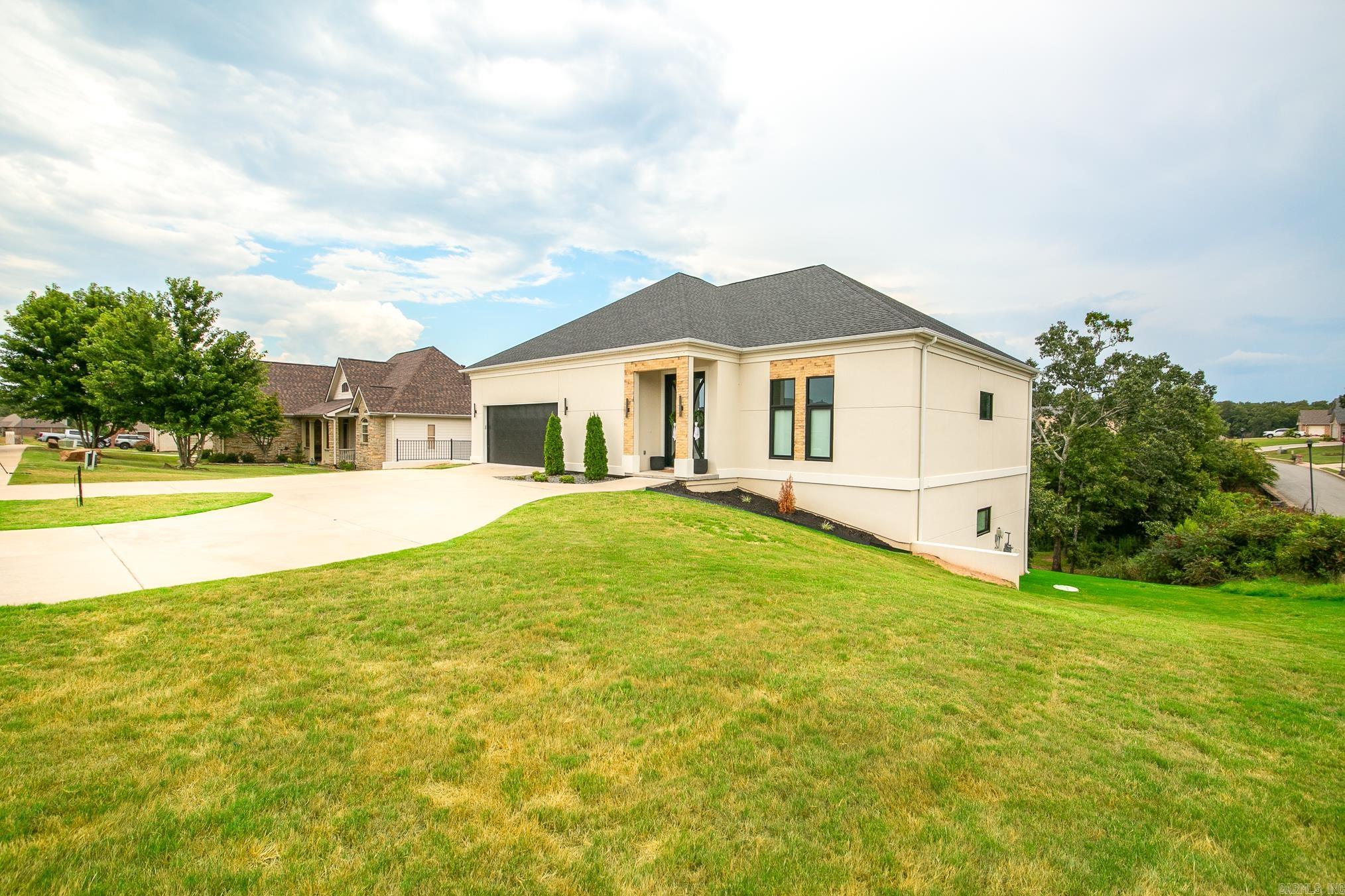 Luxury, comfort and lifestyle all come together on this one!  Located in one of Cabot's most sought after golf course communities, situated on a spacious corner lot. The main level features a spacious primary suite with floating double vanities, a tile walk-in shower, and a relaxing soaker tub. The primary bedroom connects to a private office that could also serve as a nursery or flex space, with additional access to the living room featuring an electric fireplace. This room could also function as a formal dining space on the main level. The kitchen is a showstopper with a waterfall island and breakfast bar, built-in refrigerator, floor-to-ceiling cabinetry, gas cooktop, wall oven, and microwave. Upstairs offers a private guest suite with a bedroom and full bath. The finished walkout basement is ideal for entertaining with a large open area, two additional bedrooms, full bath, media room, oversized drink refrigerator, finished bonus space currently used as a golf simulator area, and a fully finished workout room. Additional features include golf cart parking and beautiful water views from your backyard.