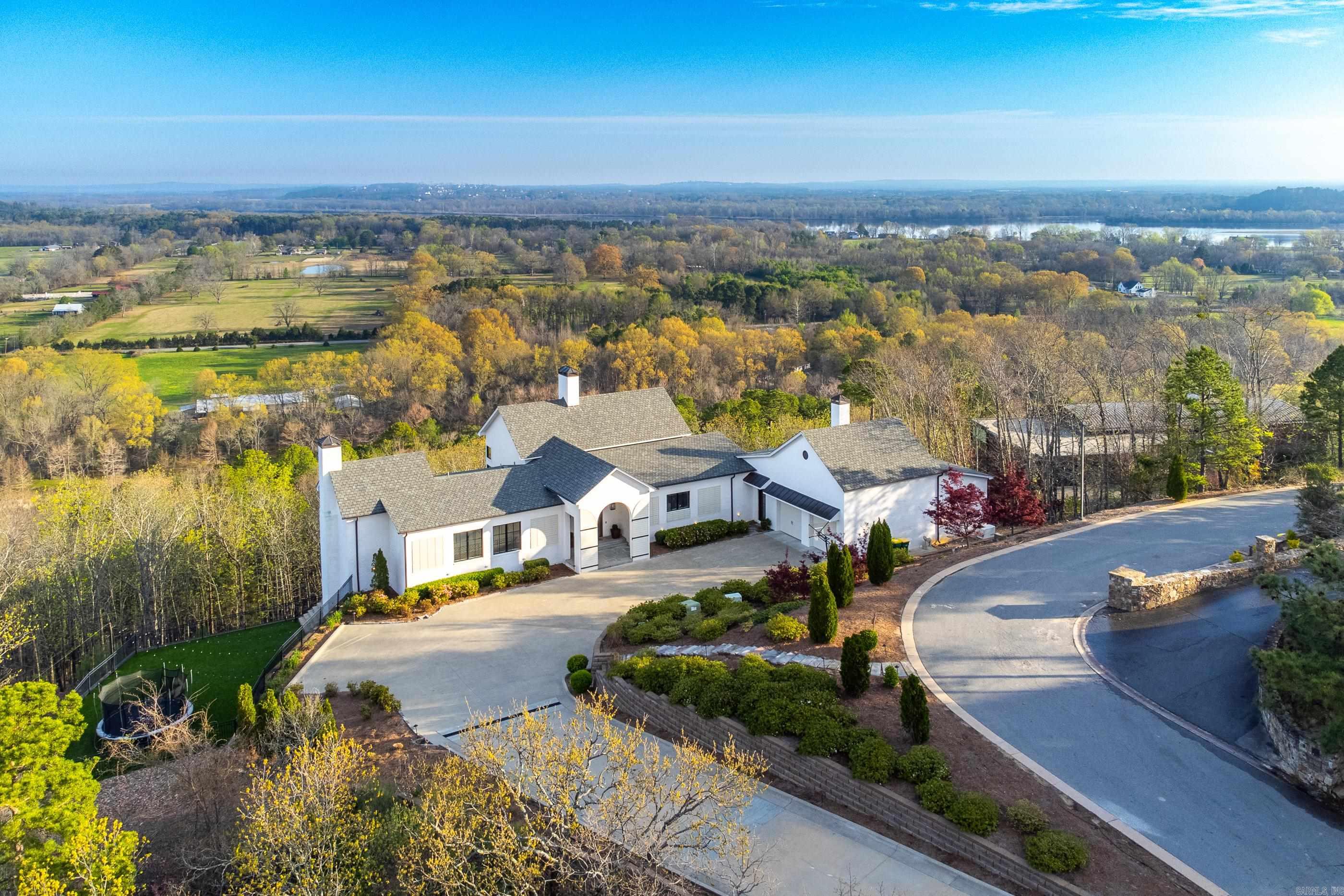 Exquisitely designed architectural marvel positioned on a 5.5-acre parcel, offering breathtaking panoramic views of the Arkansas River Valley and Pinnacle Mountain State Park through expansive floor-to-ceiling windows in the living spaces. The exterior features an impressive Infinity pool, enhanced by a vaulted ceiling covering the outdoor living, dining, and kitchen areas, ideal for hosting gatherings and elegant events. Boasting high-end appliances and fixtures throughout, the main level comprises the en suite primary that leaves nothing more to be desired along with two half baths and a hybrid laundry/butlers pantry/office that fits so many need in one space. On the lower level, a generous game room awaits, accompanied by three bedrooms, an office (or fifth bedroom), two full bathrooms, and an additional half bath, as well as a second laundry room, a workout/bunk room, and a play area with synthetic turf. Crafted by esteemed architects Jim and Ellen Yeary and meticulously built by Bill Parkinson.