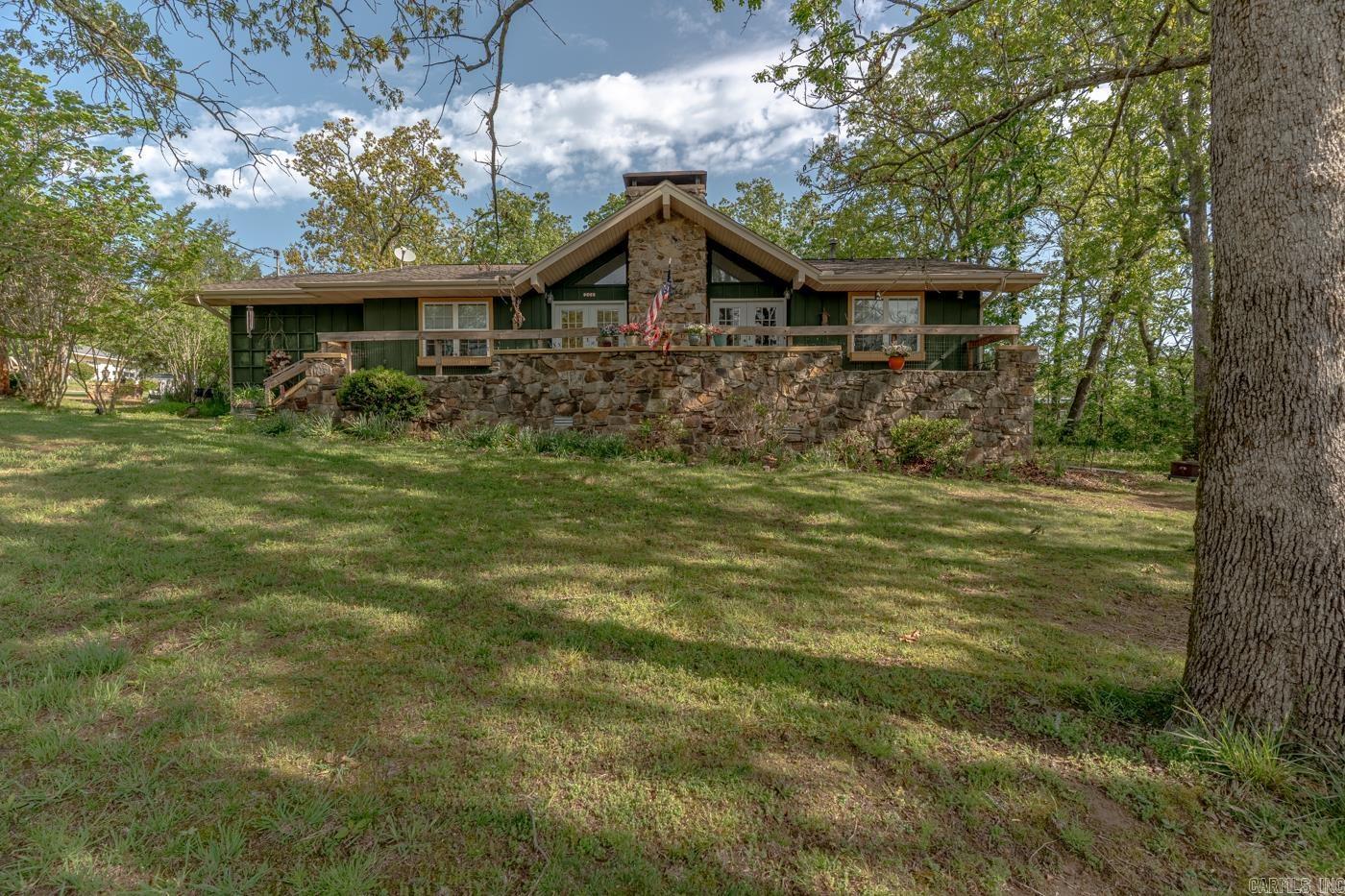 Welcome to Market 208 Fairway Dr. in Horseshoe Bend, AR. Situated on 1 +/- acre across 3 corner lots sprinkled w/ mature trees is a 1975 Ranch style home w/ Craftsman style elements. The exterior is wrapped in wood & stone and accented by renovated front & back decks, window boxes, guttering, and landscaping. The interior features 1,927 sf of well laid out living space over a split floor plan and contains a living/dining area w/ built-in shelving, vaulted ceiling lined w/ wood beams, sparkling chandeliers, and a cozy gas fireplace. The galley style kitchen offers butcher block countertops, pull-out drawers, gas range, and stainless steel appliances. Enter the Master wing through the sliding barn door to find a walk-in closet and en-suite w/ walk-in shower. The spare wing holds 2 generous bedrooms and a spare bathroom w/ shower/tub combo. A sitting room, sunroom w/ potbelly wood burning stove, and laundry room w/ Butler’s Pantry complete the layout. You’ll love the walk-in crawl space for storage, greenhouse, raised garden beds, 10x20 shop w/ loft storage and deck, frequent wildlife of birds & deer, and nearby lakes, golf courses, and trails. Call today to make this house your home.