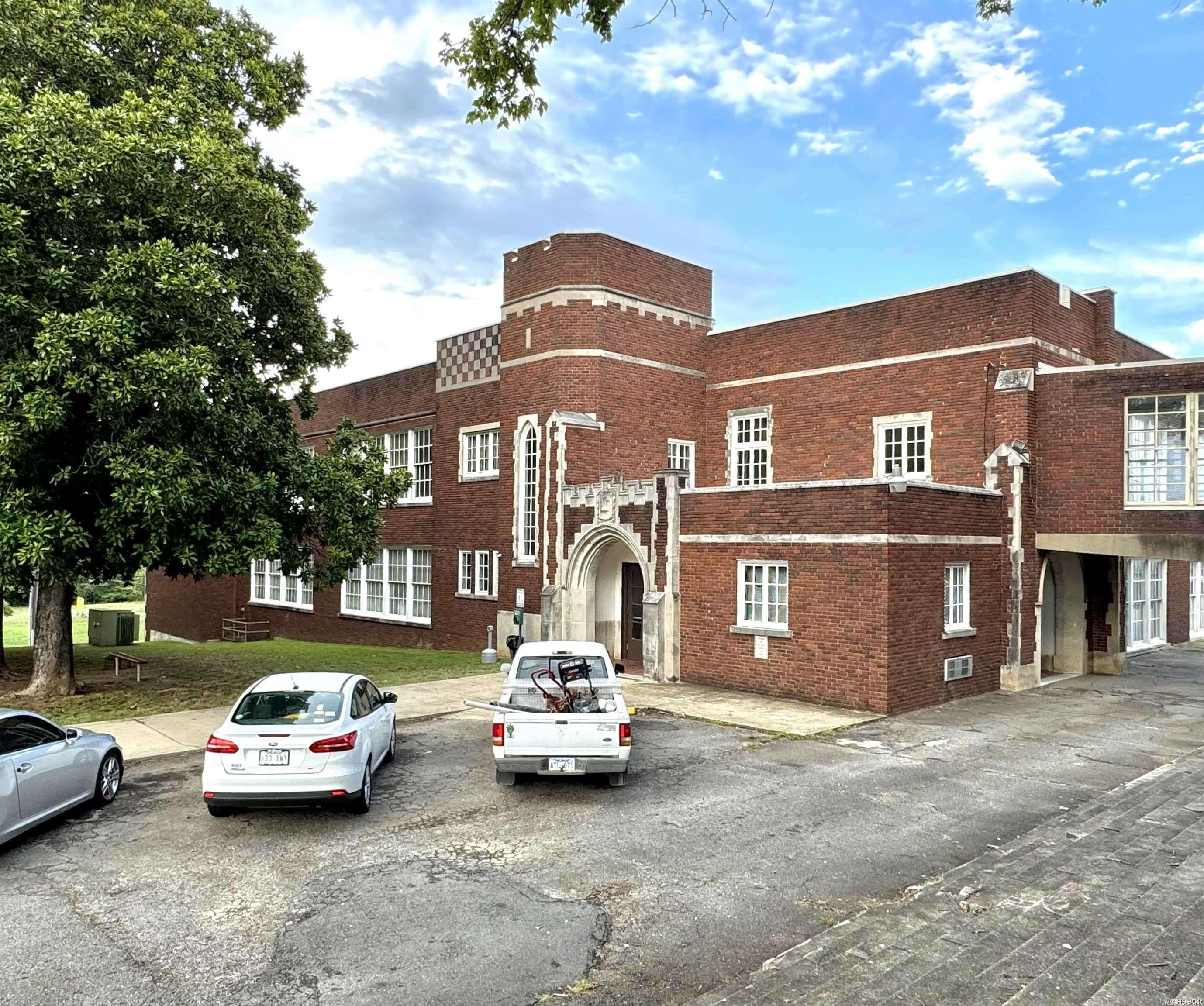 Built in 1925, the former Hot Springs High School annex building is part of Hot Springs' history. Famous for being the school attended by former President Bill Clinton, the building has been converted into 38 loft-style apartments, offering a variety of charming, well-designed units consisting of four 2BR/1BA units, four 1BR/1BA units and thirty loft-style units.  Currently 37 of the 38 units are occupied, providing immediate rental income, while one unit is undergoing repairs and will soon be ready for a new tenant. A portion of the old gymnasium has been transformed into apartments, with ample space to add up to 8 smaller apartments or 4 larger apartments. Alternatively, the gym could be repurposed as a recreation area for tenants. The building features a shared on-site laundry facility and a fire suppression system for added safety. The building is commercially zoned and given its prime location near downtown Hot Springs, these apartments would also make excellent short-term rentals. The property offers on-site parking, supplemented by an additional parking lot across the street which is included in the sale. Historic tax credits may be available for improvements.