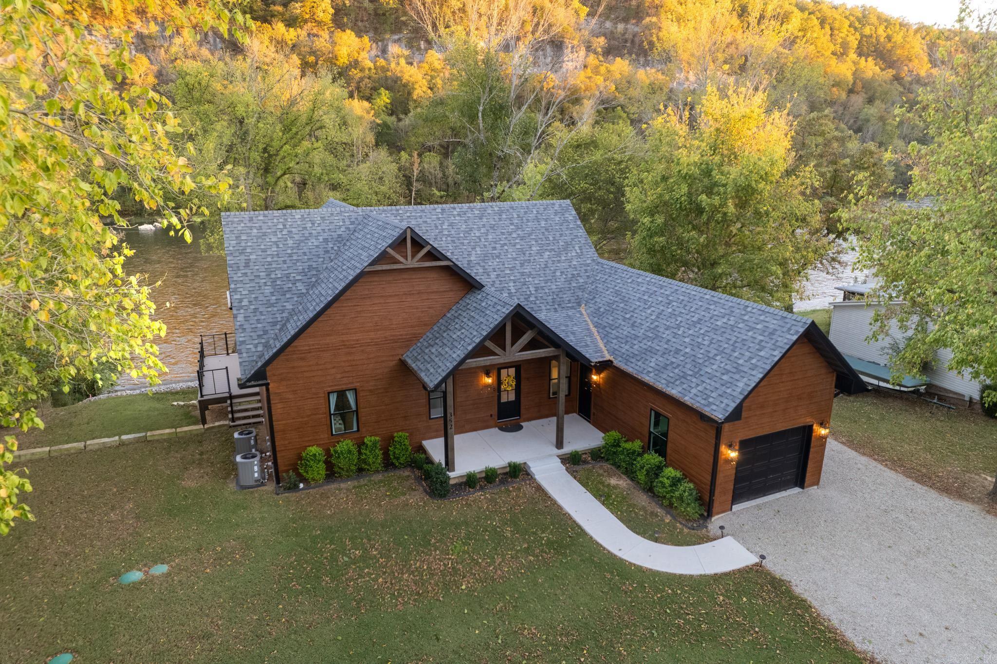 Experience luxury riverfront living in this 4BR, 2BA home in a peaceful and picturesque location with unobstructed views of the White River and rock bluffs.  Enjoy outdoor living at its finest with a beautifully crafted flagstone fire pit, private observation deck, and flagstone steps leading to one of the area’s popular fly-fishing spots near Wildcat Shoals. The exterior showcases low-maintenance Diamond Kote siding, an expansive aluminum deck with cable railing, and a gapless upper deck that provides a dry patio area underneath. Additional outdoor features include a motorized flip-down TV mount, and rock slope stabilization. A modern, rustic aesthetic welcomes you with wall of windows, beautiful woodwork and vaulted ceilings showcase the spectacular views. A spacious lower level with a second living area, laundry room, bathroom, and two bedrooms with river views, plus a flex/hobby/safe room for added versatility. Quality construction and thoughtful details include two HVAC units, spray foam insulation, solid core doors, and poured concrete basement, ensuring comfort and durability year-round.