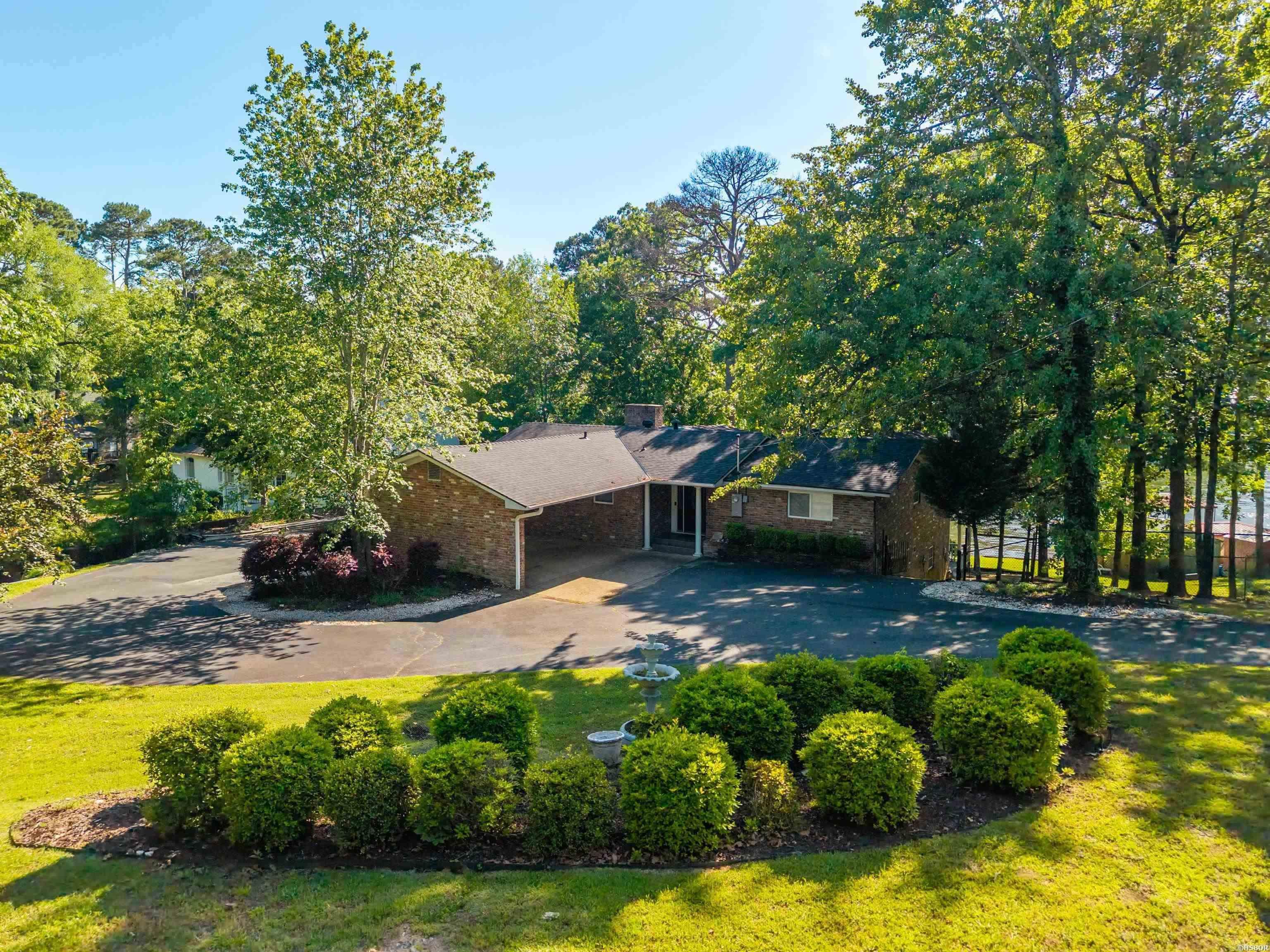Tucked away on a large 1-acre waterfront lot, this fully remodeled and furnished lake home delivers the ultimate blend of privacy, convenience, and income potential. Offering 4 bedrooms, 3 baths and 2,648 sq. ft., the home features vaulted ceilings with exposed beams, brick fireplace and an open living area designed around the spectacular lake views. The updated kitchen includes quartz countertops, oversized island seating and modern finishes throughout. Outside, enjoy mature trees, professional landscaping, expansive outdoor living space and a covered boat dock in a quiet cove setting. The active short-term rental license adds exceptional flexibility for personal use or investment purposes. The lot will easily accommodate a separate guest house or large shop building.