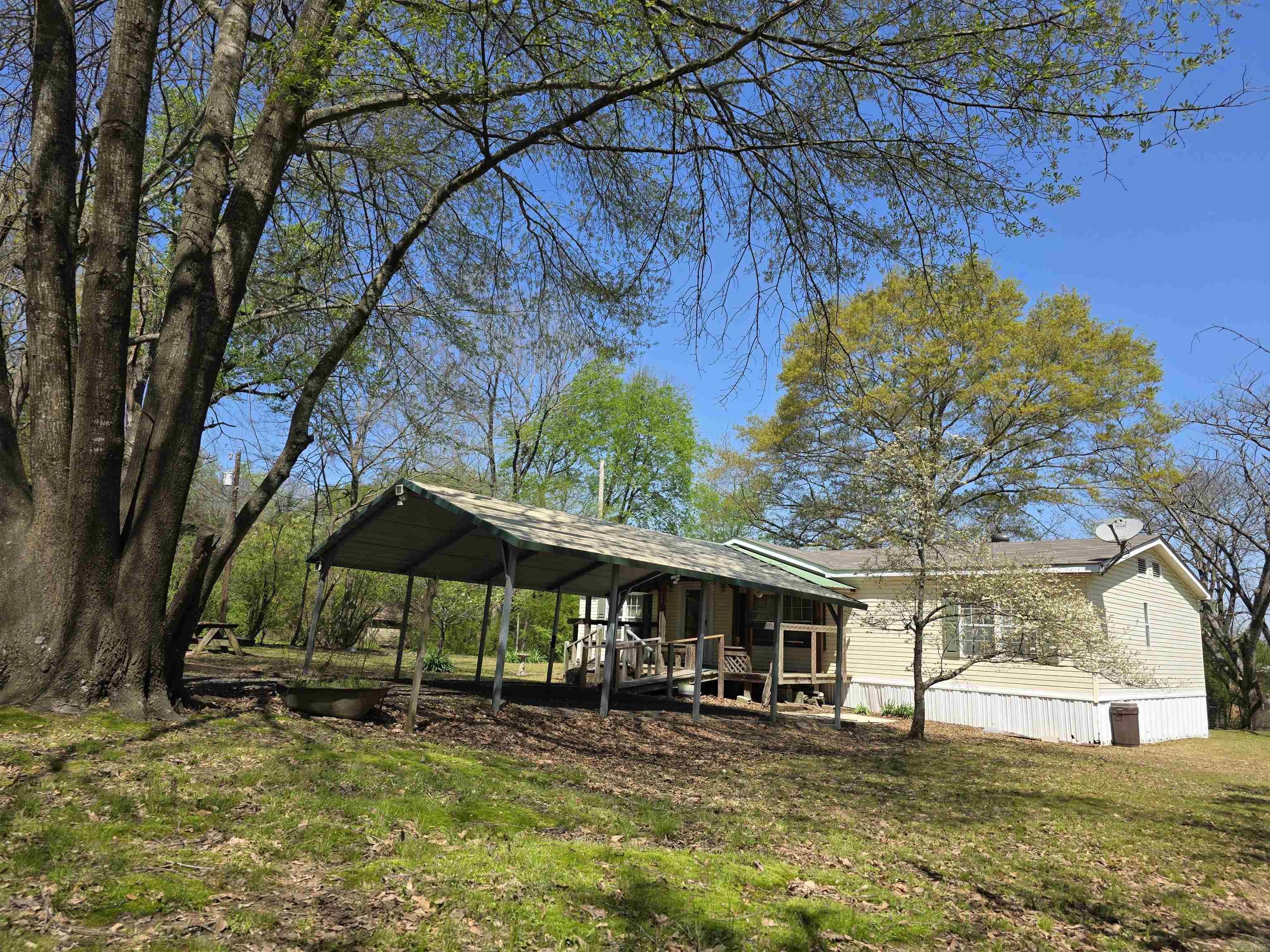 Approximately 1-acre lot in downtown Hatfield improved with a 3-bedroom, 2-bath double-wide manufactured home built in 2000. Recent updates include a new HVAC unit installed in 2024 and a newer roof, offering important system improvements for the next owner. The home is all-electric, with plumbing in place for a propane space heater in the living room if desired. The property is located within a short distance of local cafés, a convenience store, post office, city hall, and the fire station, providing convenient in-town access. Exterior features include a two-car carport, covered front deck, older well, and mature shade trees that enhance the yard. Agents: please see remarks for additional details.