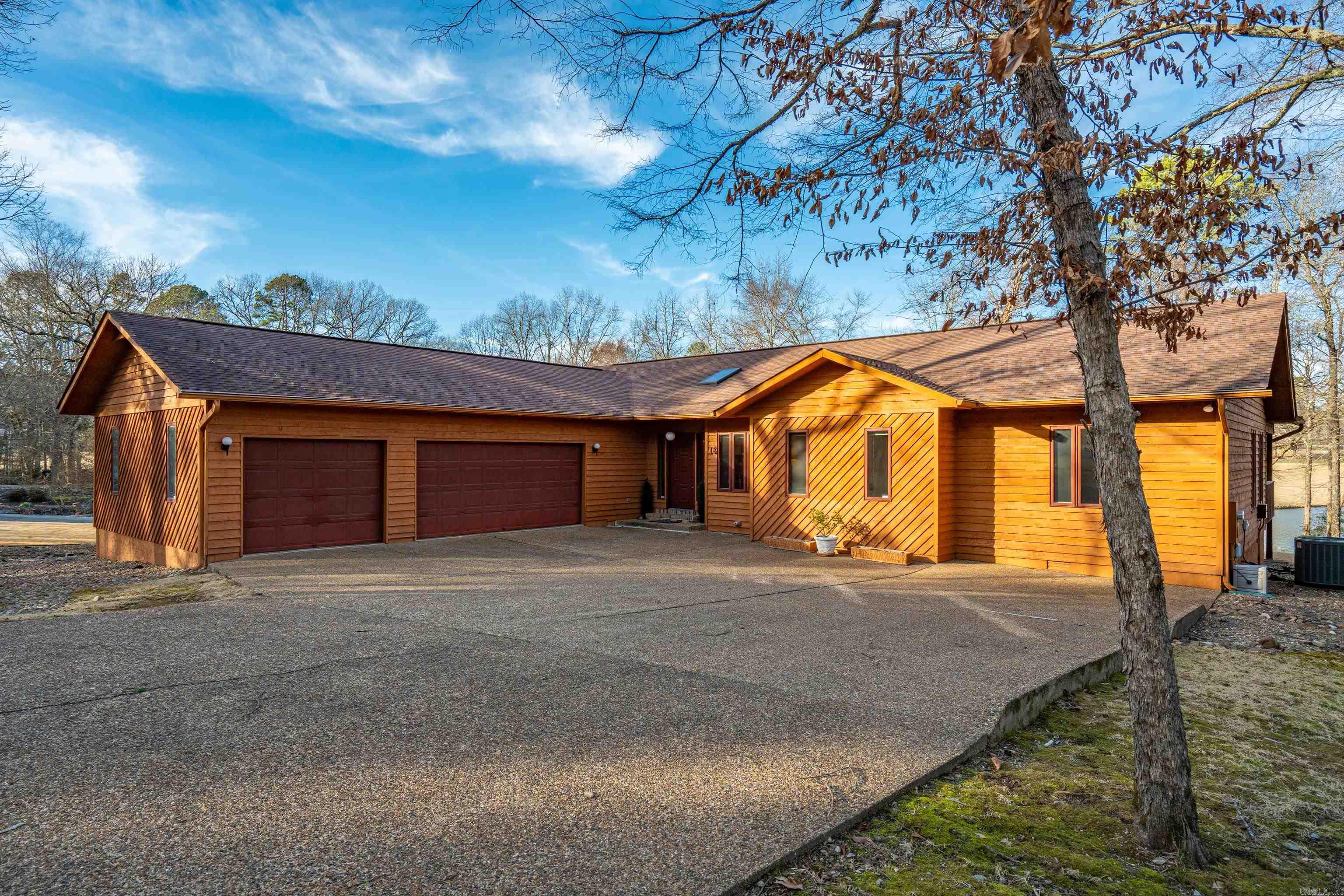 GOLF FRONT LIVING WITH DYNAMIC WATER FEATURE VIEWS! This one-owner home is ideally positioned on a relatively level, easy-maintenance lot offering sweeping golf course frontage paired with beautiful lake views. Rustic wood finishes and vaulted ceilings create warmth and character throughout the spacious one-level layout. A three-car garage provides ample room for vehicles, storage, and hobbies. The Arkansas room showcases a stunning wall of windows, filling the home with natural light and capturing the ever-changing outdoor scenery. The split floor plan offers privacy, with a generous primary suite separate from guest spaces. Office or third bedroom includes an area designed for a future closet, allowing flexible use. Enjoy both a formal dining area and a breakfast area, along with a spacious living room ideal for entertaining or relaxing after a day on the course. Located in Hot Springs Village, this super convenient location provides quick access to golf, lakes, fitness centers, trails, and all Village amenities, delivering comfort, views, and lifestyle in one exceptional property. Perfect for full-time living or vaca retreat! NEW ROOF!