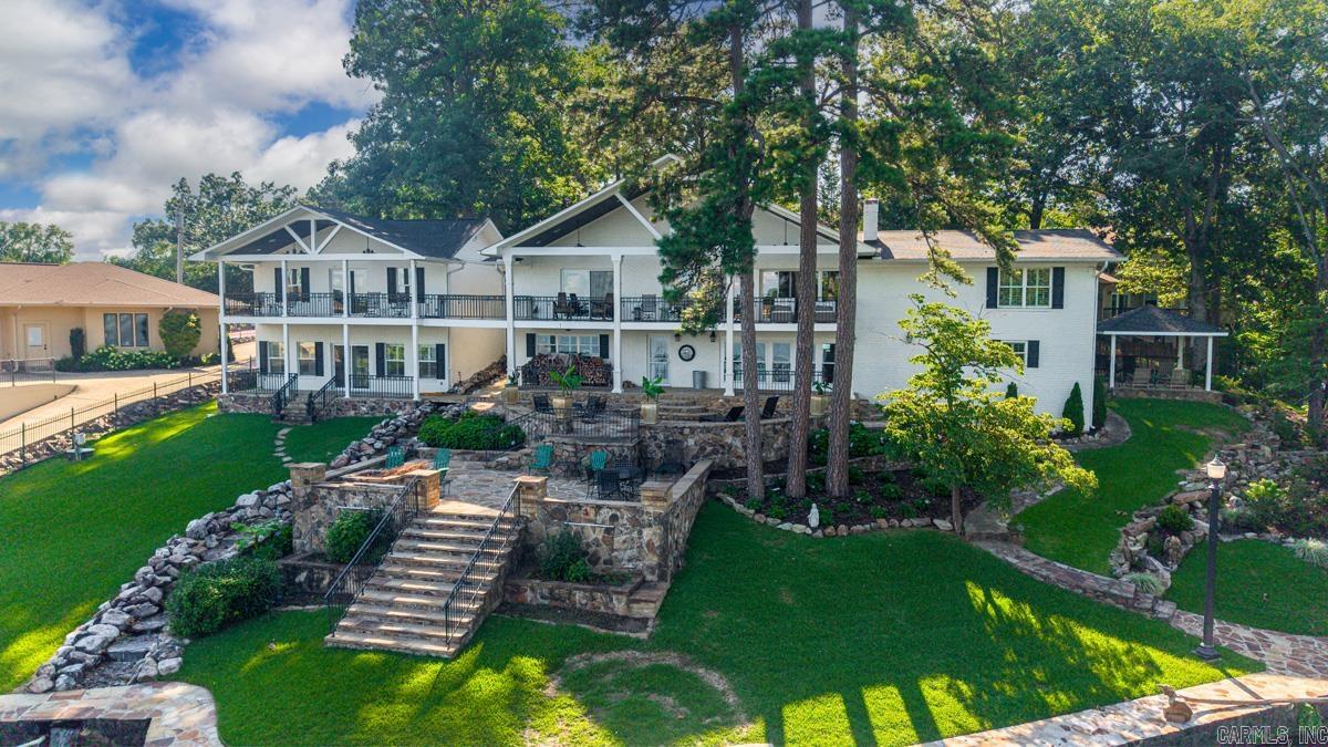 Welcome to this exceptional Lake Hamilton estate where timeless craftsmanship meets effortless waterfront living. Extensively remodeled in 2016, the main home showcases custom hand-scraped hardwoods, top quality finishes, and thoughtfully designed living spaces with captivating views of the lake. The separate 1,200+/-sqft bungalow, built in 2018, features 2 bdrms and 1.5 ba, hospitality kitchen, laundry, and living space. Perfect for guests, family, or multi-generational living. Both the main home and bungalow received new roofs in 2023. Together the property offers 7 bdrms and 5.5 ba, 1 full kitchen, 2 hospitality kitchens, and 3 laundry areas making it ideal for entertaining or hosting! The outdoor living is just as impressive with an expansive balcony, lower rock patio complete with fire pit, plus a private,  covered 2 slip boat dock w lifts and 2 jet ski ramps. Whether you're searching for a luxury primary residence, a weekend escape, or an exceptional investment opportunity, this rare Lake Hamilton home offers the space, quality, and setting to create unforgettable memories for generations to come!
