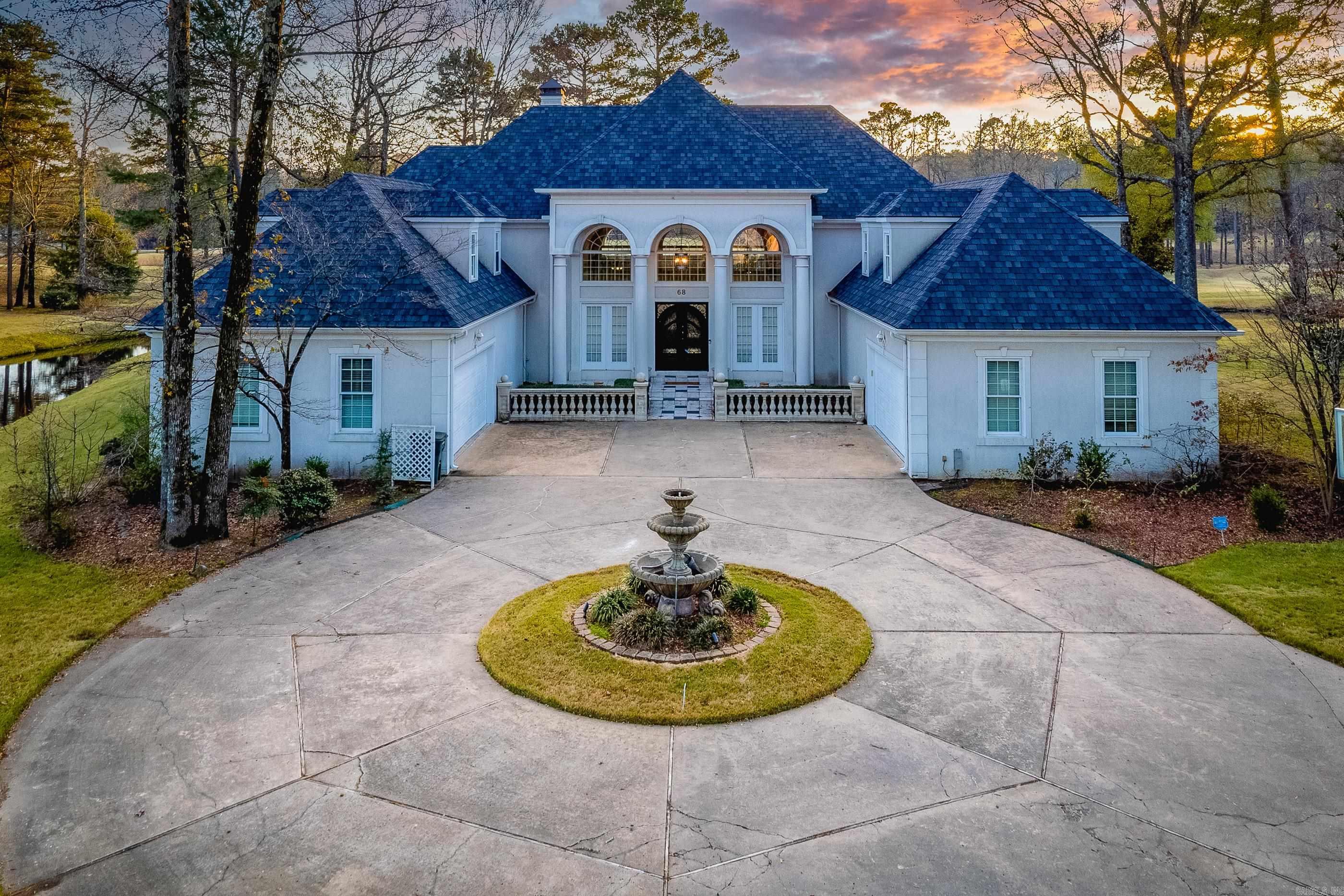 Impressive, architecturally designed home offering exceptional style, function, and breathtaking views. The welcoming foyer opens to a grand living room with gas fireplace, soaring ceilings and a flexible area ideal for formal dining or a piano. A stunning wall of windows and doors spans the back of the home, leading to the sunroom and an expansive covered deck overlooking the golf course and lake. The chef's kitchen showcases Viking appliances, a huge central island, honed and polished granite, a second prep kitchen, informal dining, and open to a warm hearth-room den. The main level primary suite is a true retreat with a gorgeous spa inspired bath, coffee bar, and an adjoining sitting room or gym. A separate guest suite, private office, half bath and well appointed laundry complete the main floor. Upstairs offers four oversized bedrooms, three baths, a spacious game room, and a veranda stretching across the back of the home to capture the views. Additional highlights include a charming fountain water feature, circular drive, striking iron and glass double doors, two garages accommodating four cars, and beautiful vistas from nearly every room. Come see!