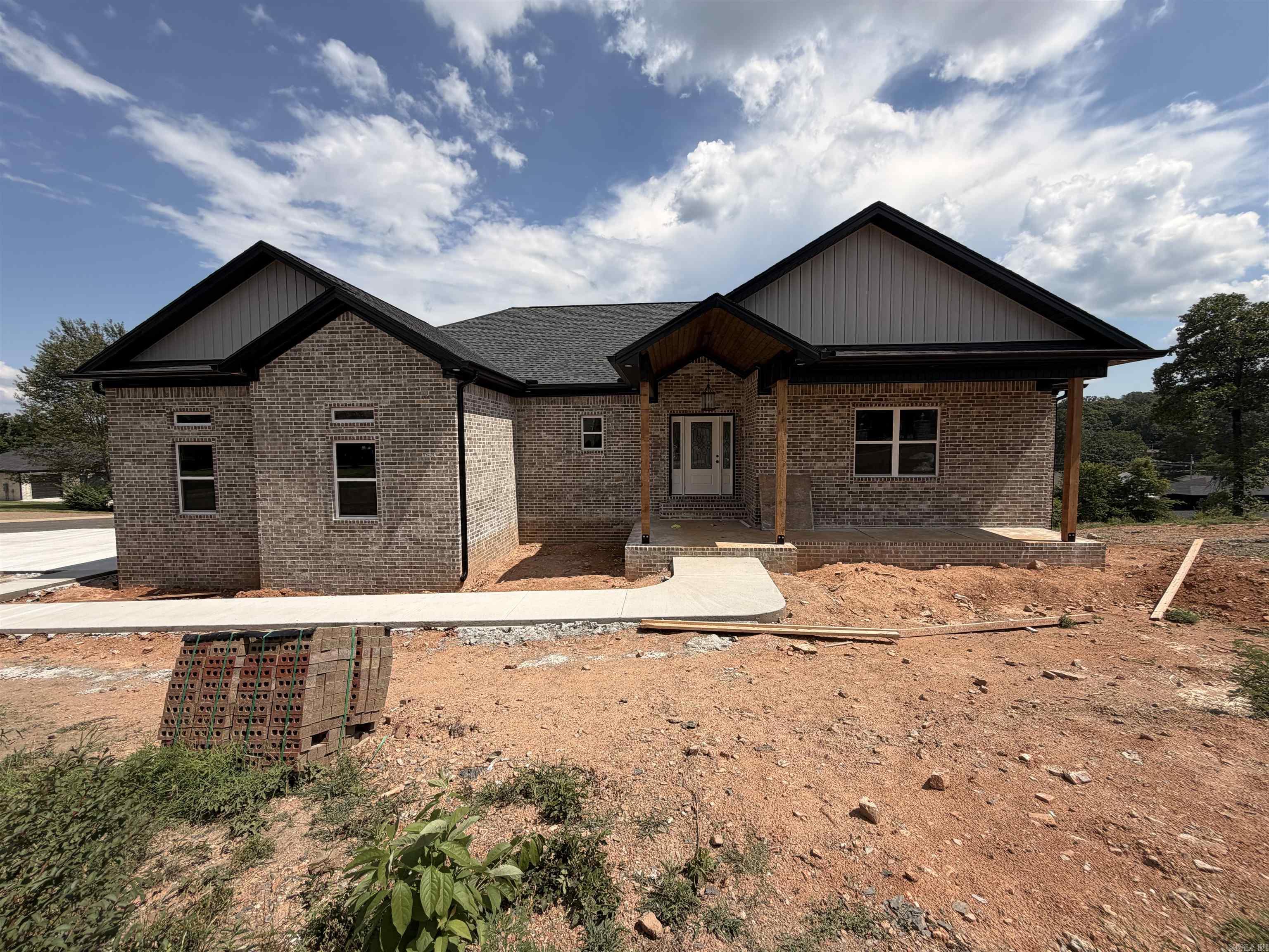 Welcome to Cougar Terrace — a stunning new construction home in an established Hot Springs subdivision where modern luxury meets exceptional craftsmanship. From the moment you enter, soaring cathedral ceilings and a breathtaking floor-to-ceiling rock fireplace set the tone. The chef-inspired kitchen features granite and quartz countertops, gas cooktop with pot filler, wall oven, built-in microwave, granite composite sink, tile backsplash, and black Delta hardware throughout — plus a spacious walk-in pantry with a Costco door for effortless storage. The 90 sq ft laundry room is a luxury in itself, with custom cabinetry, granite folding counter, utility sink, and a dedicated dog wash station. Most of the home is painted in Universal Khaki, the Color of the Year, creating a warm, timeless atmosphere throughout. The downstairs bonus space features a mini-split system, sink, full-size refrigerator, under-counter ice maker, and closet — perfect for entertaining or a guest retreat. Step outside to a 260 sq ft patio with railing. Additional highlights include custom tile showers, tankless gas water heater, and designer lighting. The neighborhood has lake access with a community boat launch
