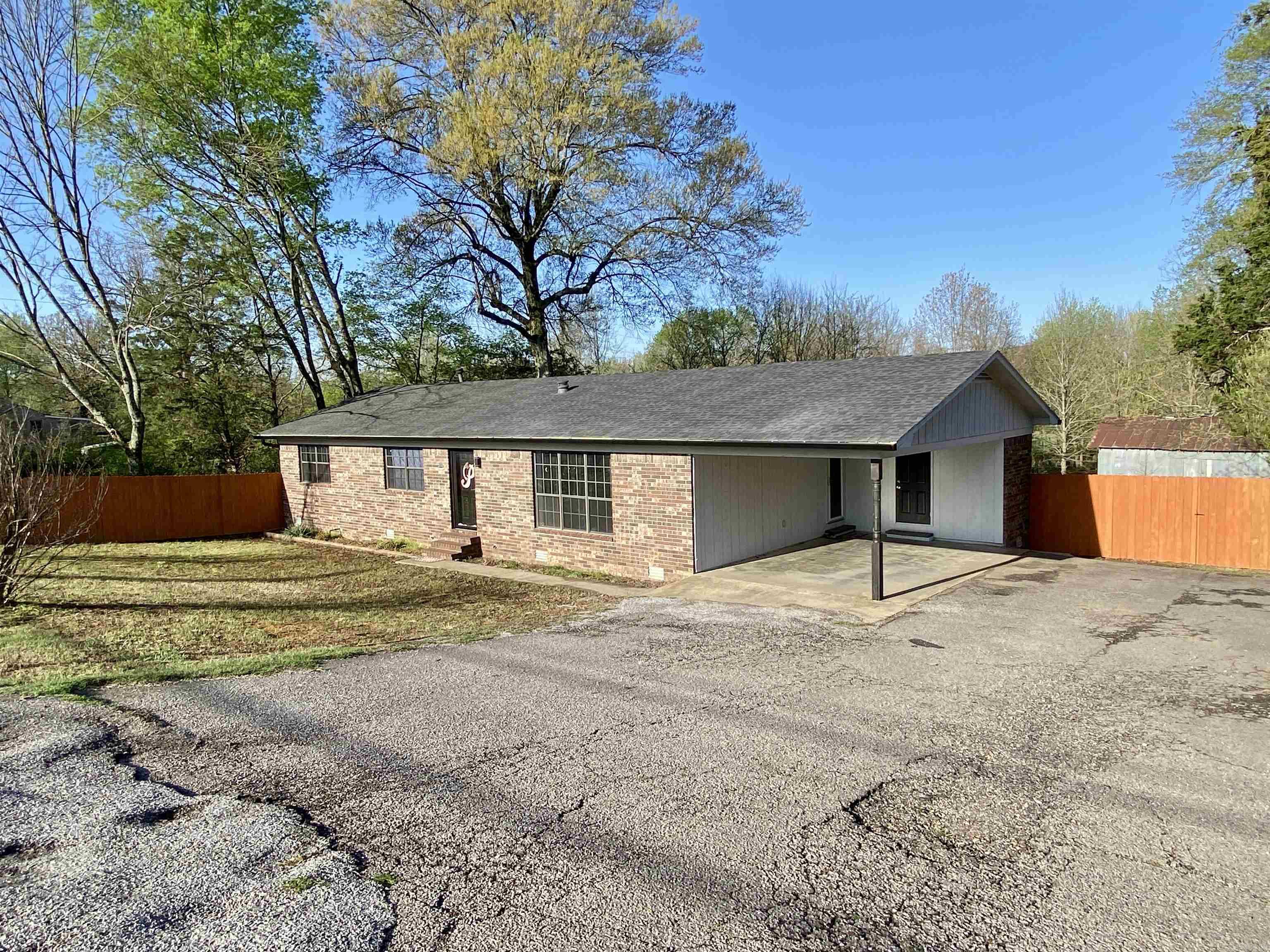 Recently updated and move-in ready, this 3-bedroom, 2-bath home sits on 1 acre at the edge of town with few neighbors, offering privacy and peaceful views. A covered back deck overlooks adjoining woods and pastures, while shade trees and a fully fenced yard add to the charm. Inside, you'll find a modern design with a spacious living room featuring built-ins, floating shelves, and vaulted ceilings with exposed beams. The eat-in kitchen is fully equipped with stainless steel appliances, solid surface countertops, bright white cabinetry, and a breakfast bar. Additional updates include a new roof, LED lighting, luxury vinyl flooring, and a custom-tiled shower with rainmaker fixtures and designer vanities in both bathrooms. The huge outbuilding provides plenty of storage, and the spacious laundry room comes with a like-new washer and dryer set. A flat screen TV and mount are also included — just move in and enjoy!