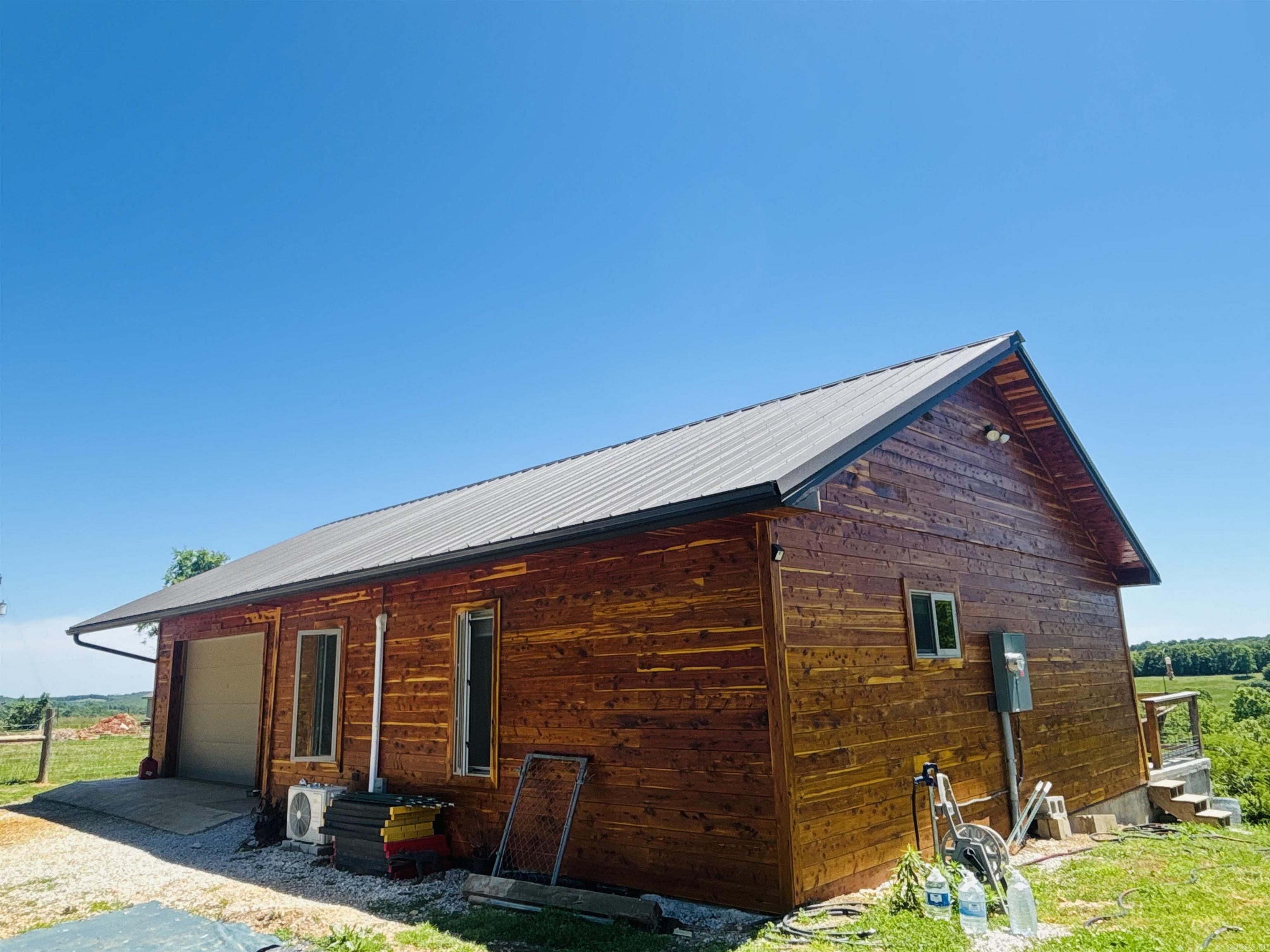 Custom-built cabin with gorgeous mountain views ideally located in the beautiful Ozarks only 30 minutes from Harrison and 45 from Mtn Home. From the moment you walk in, the views are sure to amaze or enjoy them from the back deck perfect for morning coffee or evening stargazing. This spacious and well-designed cabin features an open concept living room/kitchen, stainless appliances, all-wood cedar interior, tray ceilings, pocket doors, large quality windows with remote blinds, tile and luxury vinyl plank flooring, walk-in shower, cedar siding, metal roofing, guttering, and an attached one car garage offering plenty of room for storage shelving or work benches. The well insulated 2X6 walls and mini splits provide energy efficient heating and cooling. Fur babies? The fenced yard is pet ready, or if gardening is your passion, there is plenty of space for growing. Peaceful country living! Call today for more info or to view!