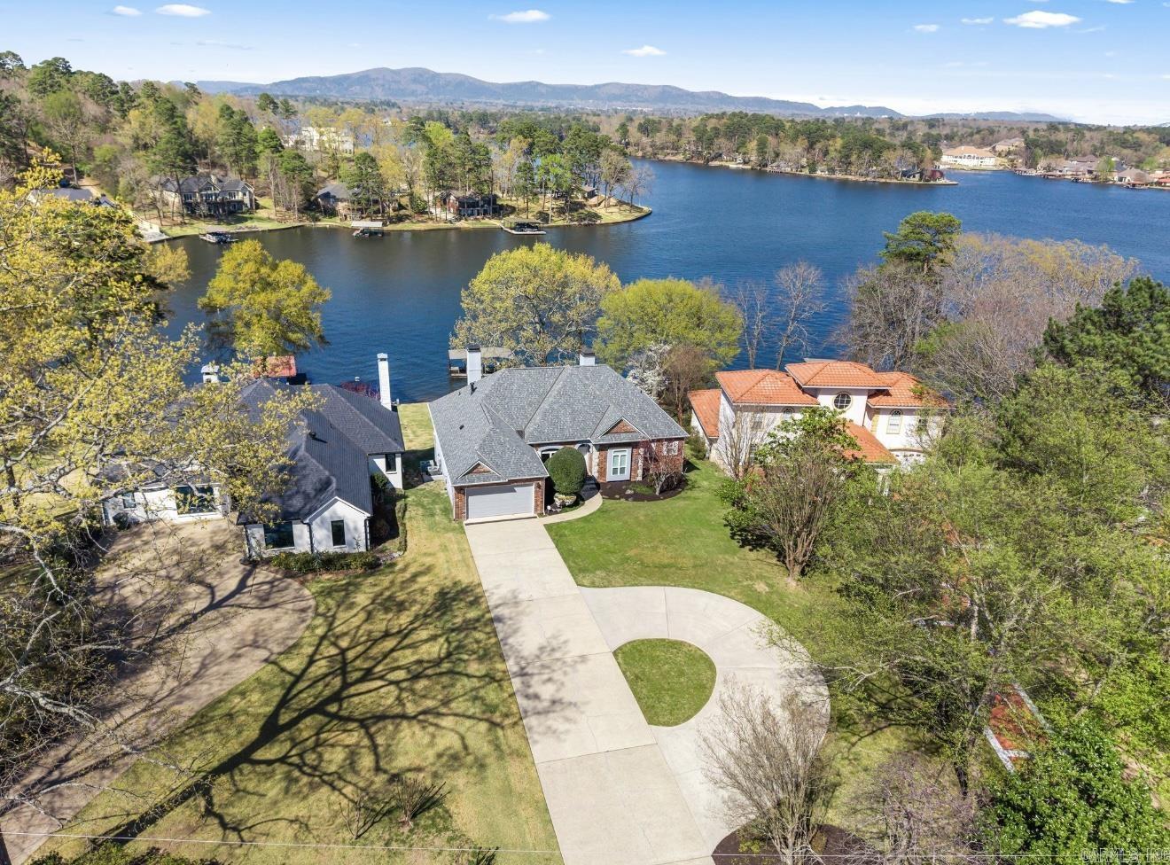 This beautifully remodeled 5 bed, 4.5 bath home offers spectacular lake views from the upper deck & the lower patio in one of the most sought-after Lakeside School District locations on Lake Hamilton. Experience waterfront luxury in this stunning two-story, 4,390 sq ft home with a 2-car garage. The moment you walk through the door, graceful elegance & a breathtaking view straight out to the water will captivate you. The thoughtfully designed living space features hardwood floors & a chef’s kitchen, crafted to exude sophistication and charm at every turn. Enjoy 2 informal living areas, 2 kitchens, a lavish primary ensuite, spacious guest rooms, office space, abundant storage, & bonus space to suit your needs. Outside, lakefront living shines with a deck showcasing panoramic views & a private 2-stall covered dock with a swim deck—offering exclusive lake access & the perfect launching point for exploring Lake Hamilton. Beyond its potential as a nightly rental, this property seamlessly transforms into an idyllic family vacation home or a luxurious primary residence that adapts effortlessly to a variety of lifestyles. Ask to see the extensive list of upgrades and schedule your showing!