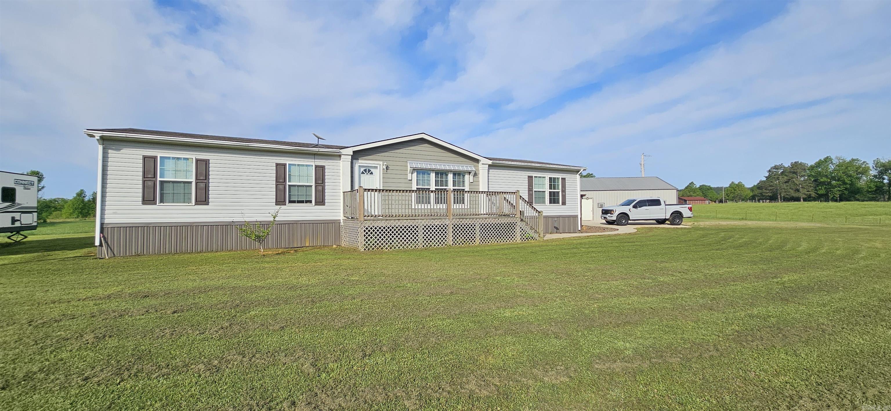 MOTIVATED SELLER! Seller willing to give a significant credit toward closing costs. Nestled in the foothills of the Ouachita Mountains, this 14.09 +/- acre property offers fenced & partially cross-fenced pastureland with endless potential. The 4BR/2BA manufactured home features an open-concept layout with split floor plan, spacious primary suite with 3 closets, soaking tub, walk-in shower, & abundant storage. Kitchen offers ample cabinetry, workspace, & separate pantry.  Outdoor improvements include a 30x30 shop with electric plus a 12x15 interior room ideal for storage, hobbies, workspace, or gym area. Acreage has been utilized for hay production in recent years & also includes a fenced 100x100 garden area. Additional custom-built 16x48 tiny home available separately or may be negotiated with sale. Features include metal roof, upgraded insulation, spray foam insulation underneath, tongue-and-groove interior finishes, LVP flooring, & tiled walk-in shower. Conveniently located near outdoor recreation areas, lakes, rivers, & national forest land.