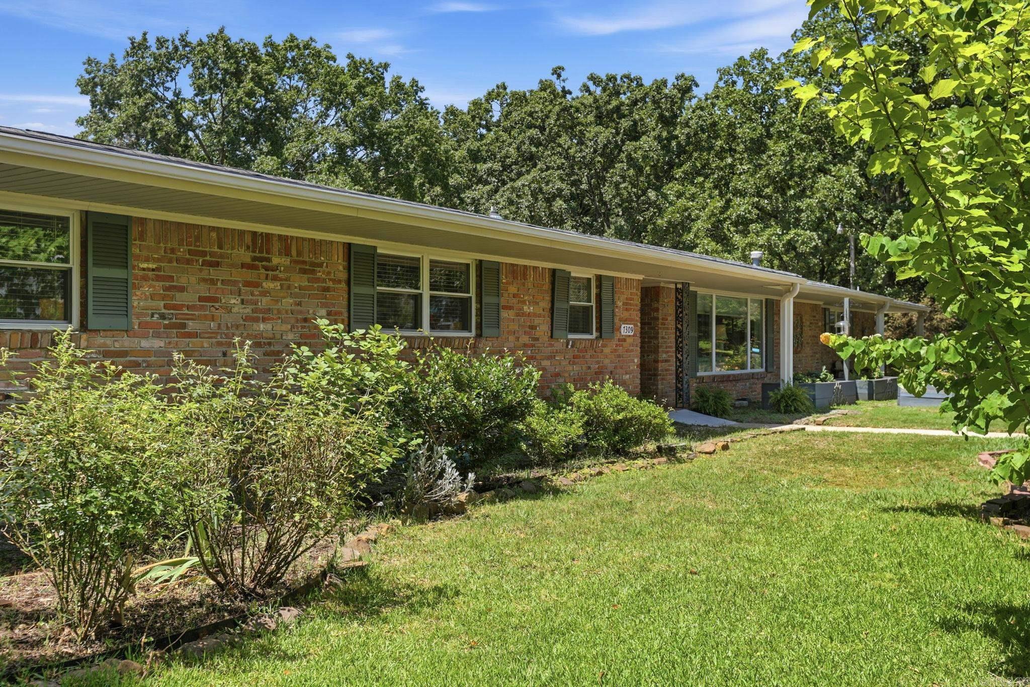Classic MIDTOWN LITTLE ROCK ranch on a large corner lot with 2,966 sq. ft., PAID-OFF SOLAR PANELS, and room to truly spread out. This SPACIOUS home offers HUGE rooms, WIDE hallways, TWO generous living areas, and an easy, flexible floor plan. The front living/dining area is filled with natural light from a large picture window, while the second living space features warm wood paneling, a brick fireplace, and doors opening to a charming brick patio/courtyard. The kitchen offers abundant cabinetry, bar seating, and a comfortable, casual feel. Located off the HUGE laundry room is a private FLEX SPACE with its own exterior entrance and a tiny full bath—ideal as an office, guest suite, studio, caregiver/nanny quarters, or hobby space. One bathroom is accessibility-minded with helpful HANDICAP-ACCESSIBLE features. AC 2024/ROOF 2019. Outside, enjoy mature trees, garden beds and a large yard with wonderful curb appeal. Centrally located in Midtown near shopping, dining, medical centers, schools, and everyday conveniences, this home offers rare square footage, versatility and value in a highly convenient Little Rock location.