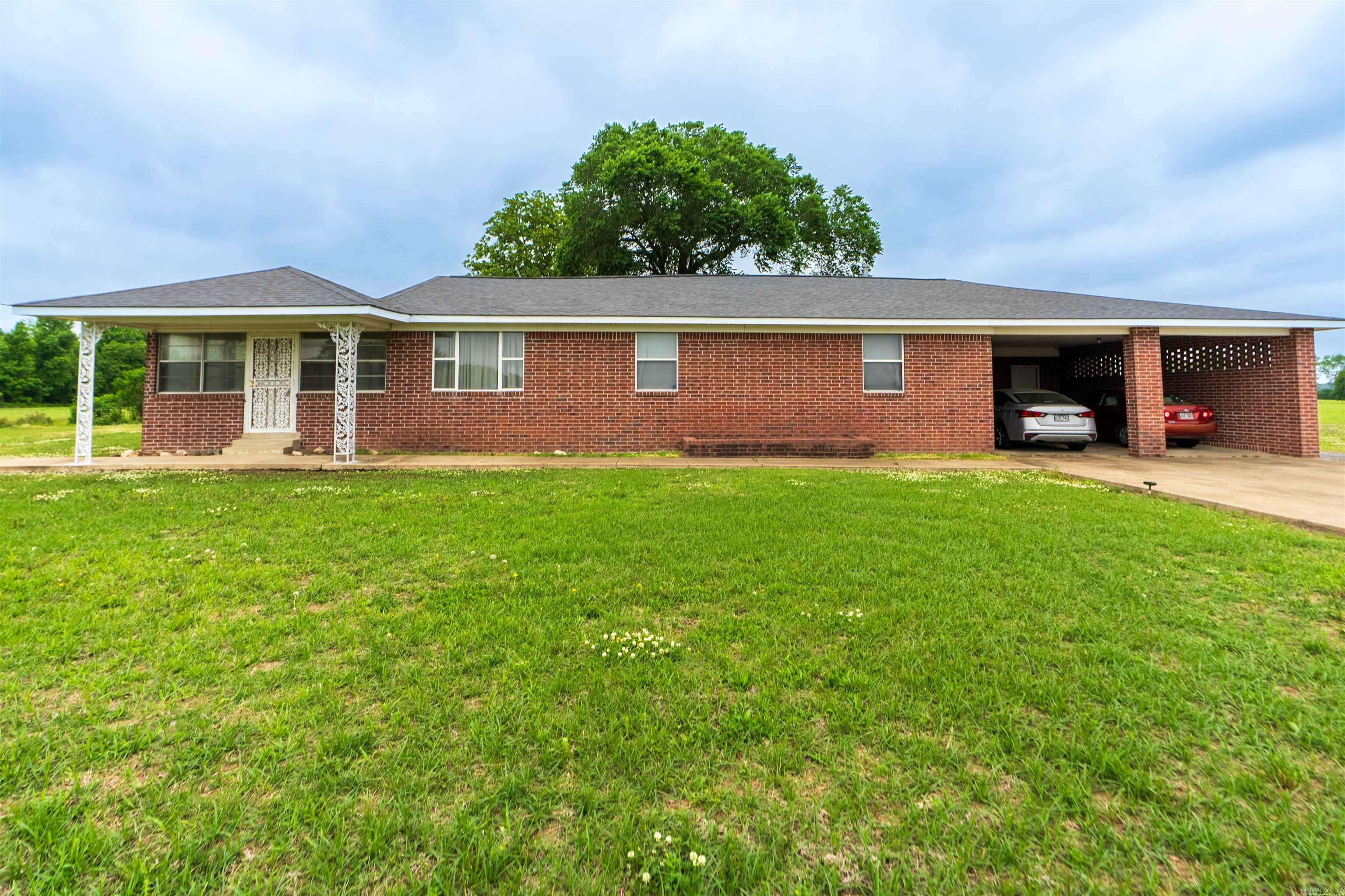 Spacious 4 bedroom, 2 full bath brick home situated on 1.53 acres offering the perfect blend of country living and functional space. This well-maintained property features over-sized living areas, a large kitchen with abundant cabinet and counter space, and multiple gathering areas ideal for everyday living or entertaining guests. The home offers a comfortable layout with generously sized bedrooms, plenty of natural light, and classic charm throughout.  Outside, enjoy the peaceful rural setting with open views, mature shade trees, and plenty of room to spread out. The attached covered parking area provides convenience and additional storage space, while the enclosed sunroom offers a great spot to relax year-round. Whether you are looking for room for a growing family, space for hobbies, or simply a quiet country setting, this property has endless potential.  If you have been searching for a solid brick home with acreage and space both inside and out, this one is worth a look.