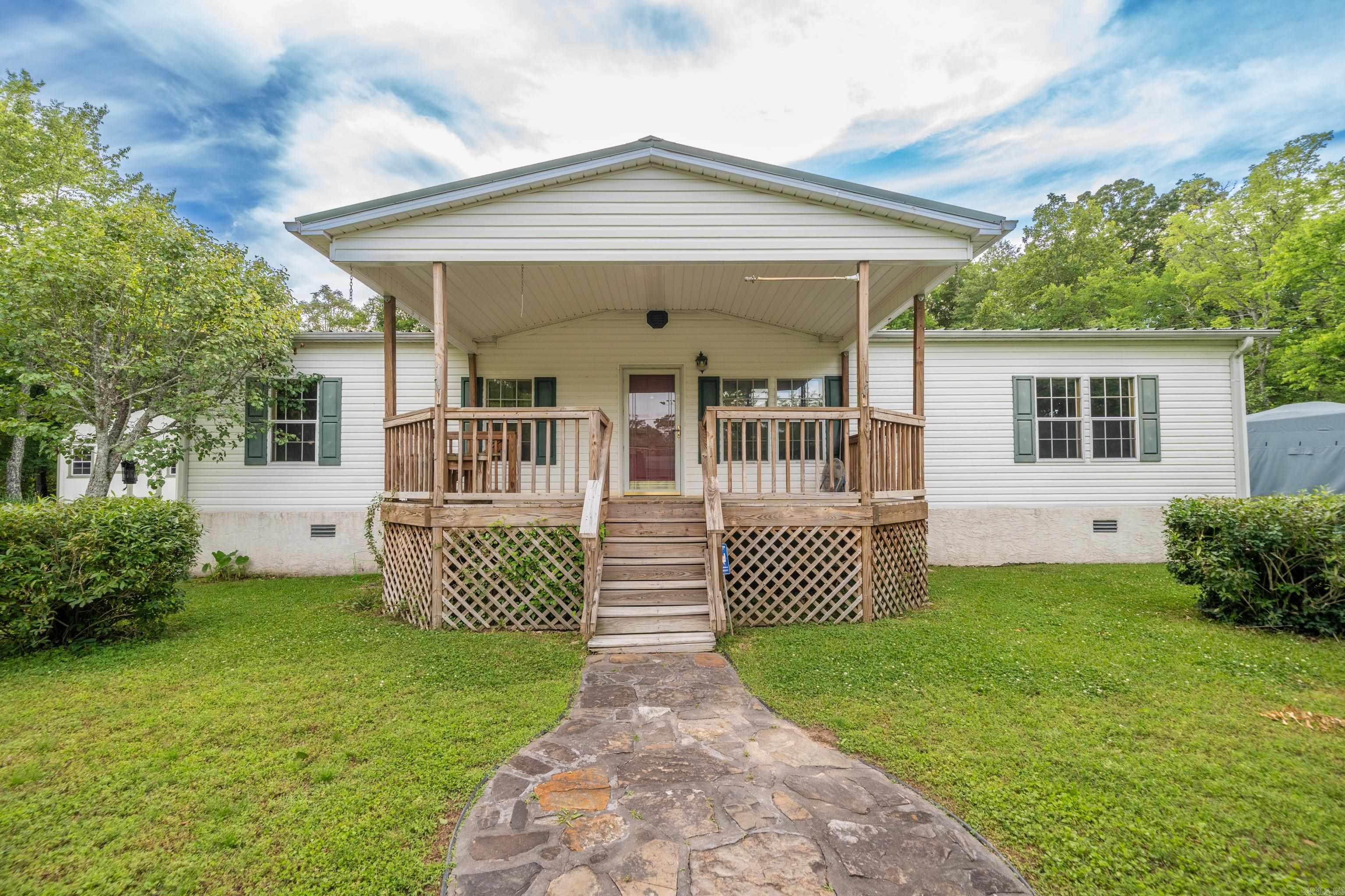 Well-maintained triple-wide manufactured home on almost half an acre with fresh paint and new flooring throughout. This home offers 3 bedrooms with a split floor plan, featuring a private primary suite. The spacious kitchen flows into the living area with a cozy fireplace. Enjoy the front porch that features a built-in bench. Two carports and a backyard storage shed provide added convenience.  **Professional Photos Coming Soon