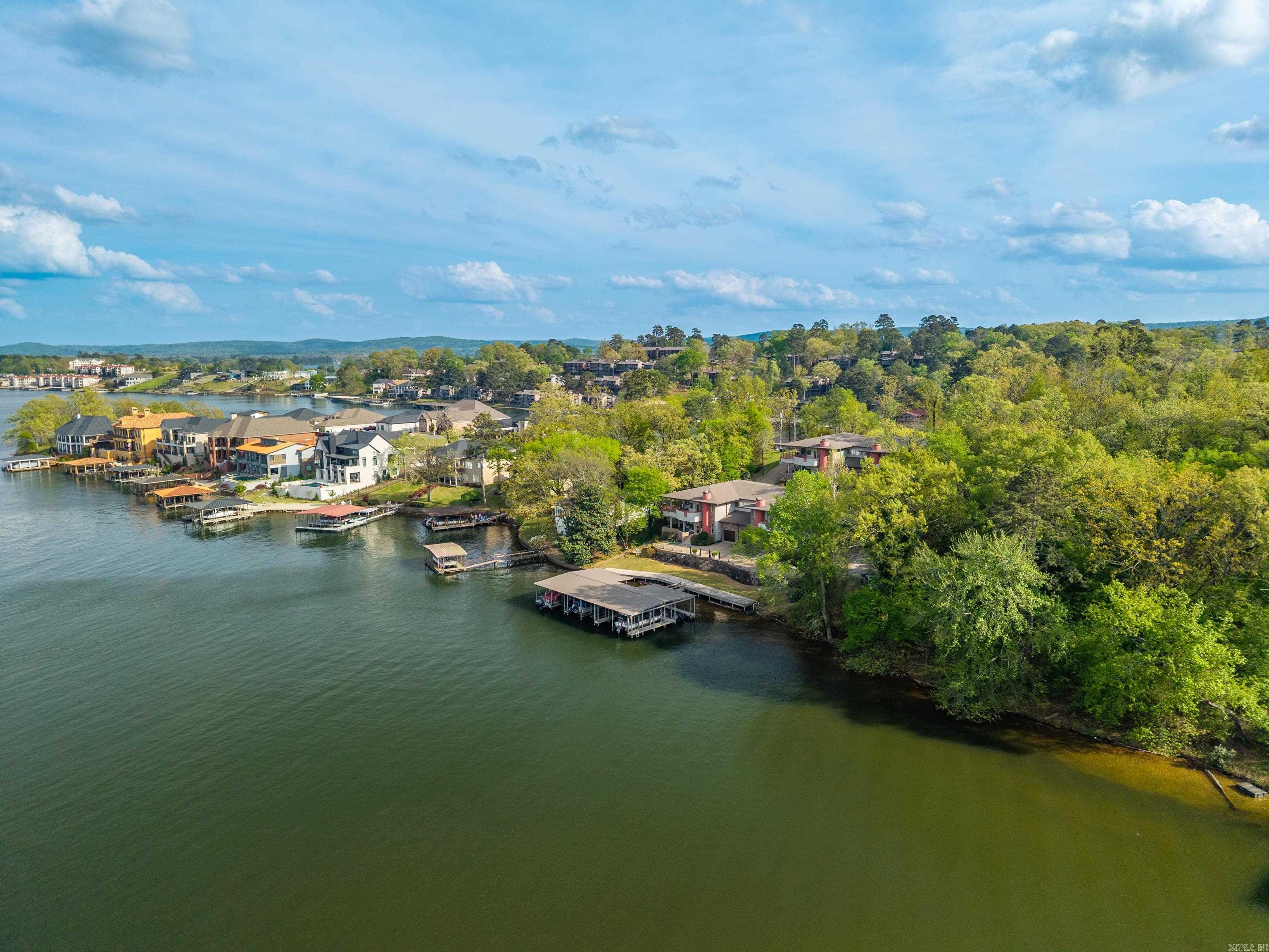 Rare opprtunity to join this exclusive condo development on Wilson Point on Lake Hamilton. The spacious unit offers 2190 square feet of energy efficency with an open concept large kitchen and living room plus office space.  The high ceilings are accented with wood for a gorgeous elevated touch, and the hallway leads you to a stunning mural in the reading nook.  There are 3 bedrooms, 2 full bathrooms plus a half bath and separate laundry room. The primary suite has a large walk in closet and oversized bathroom.The unit also has as garage for protected parking plus extra storage. Enjoy maintenance free linving while soaking up the lake views and water feature from you covered patio or cozying up to the fireplace during the winter.HOA covers not only covers the Roofs but also covers all exterior materials of the structures as well. The $600 Monthly HOA covers Water, Sewer, Trash, Gas (used for Fireplace), Sprinkler System, Termite.  This is not your average condo!