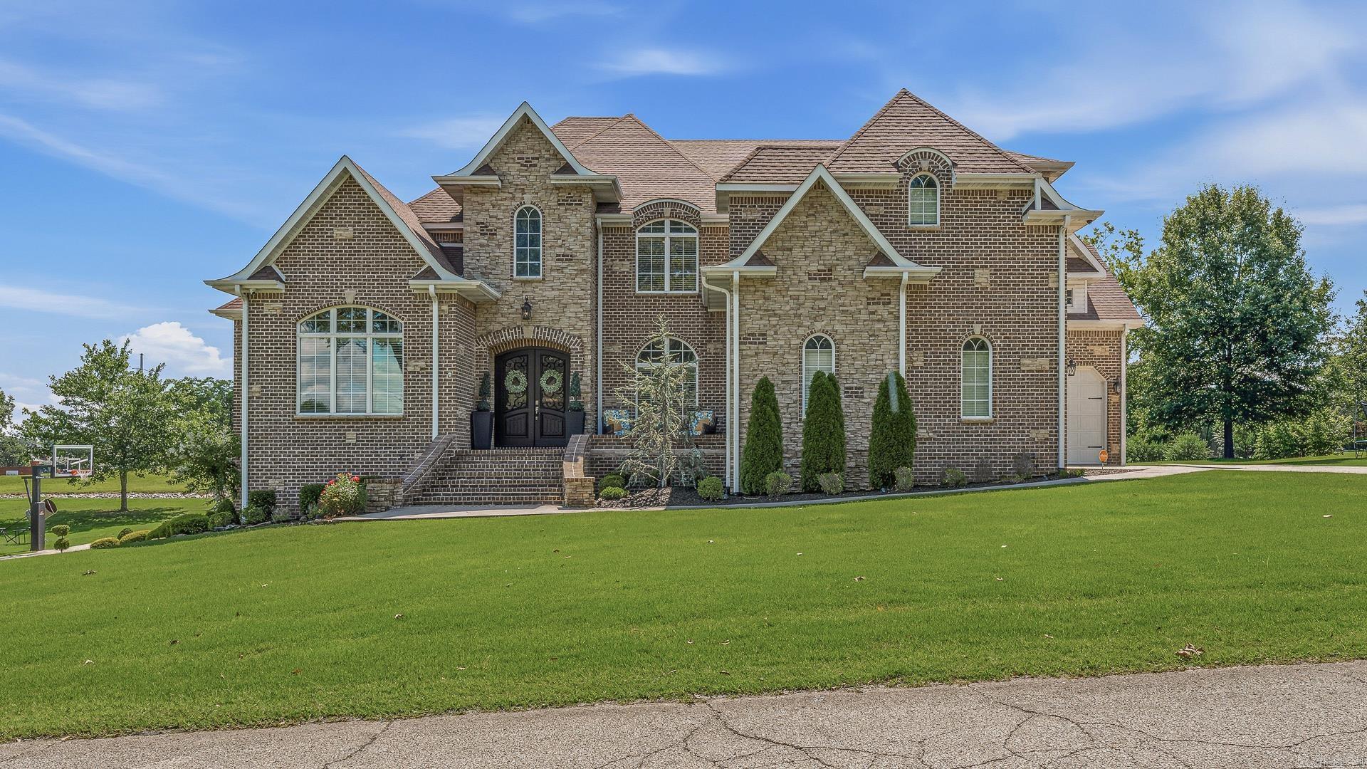 Tucked beside the Paragould Country Club golf course, this custom two-story home sits on an almost one-acre corner lot with a fully finished walk-out basement. The basement is the true showpiece, designed with a 1920s speakeasy and English pub feel. Custom millwork, handmade wainscoting, hand-scraped wood floors, reclaimed wood ceilings, brick paver accents, and two gas fireplaces create a space unlike anything else. A full custom kitchen, theater room, bedroom, full bath, half bath, outdoor kitchen, and patio area make it ideal for entertaining. The main level offers a double-island kitchen with two dishwashers, walk-in pantry, office, formal and casual living spaces, and a screened porch overlooking the property. The primary suite features a sitting area, heated bathroom floors, custom shower, custom closet, and laundry access. With multiple garage spaces, golf cart storage, high-end finishes, and thoughtful details throughout, this one-of-a-kind home was built for everyday comfort and unforgettable entertaining.