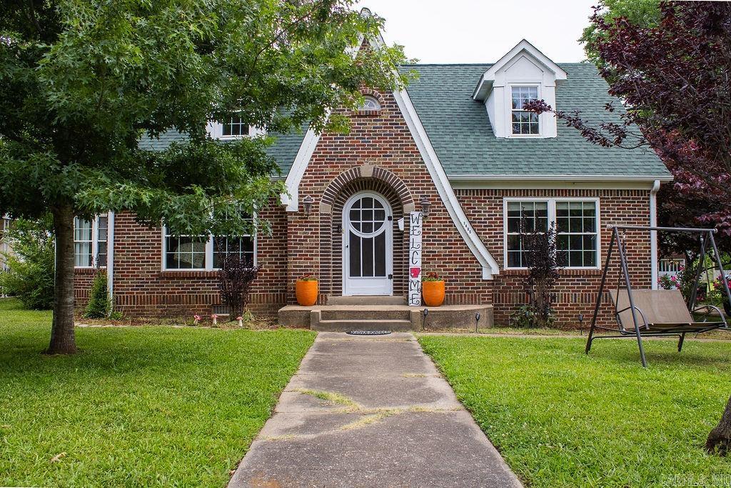 Charm, character, space, and updates come together at 1405 Hickory Ave in Mena. This beautiful Tudor Revival-style home sits on over an acre and offers over 2,000 sq. ft., 3 bedrooms, 2.5 bathrooms, a brand-new roof, updated windows, and tasteful updates throughout. Inside, you’ll find original hardwood floors, charming built-ins, unique alcoves, and a warm living room with a gas log fireplace. The bright dining room flows into an updated kitchen featuring granite countertops, stainless appliances, under-cabinet lighting, refrigerator, microwave, and new flooring. The main level includes a bedroom with built-ins and its own private bath, a half bath near the back entrance, plus an extra room that could be used as an office, hobby room, or converted into another bedroom. Upstairs are two spacious bedrooms that share a full bath. The bright laundry/sunroom overlooks the expansive backyard with a wooden privacy fence, and beyond that is another half-acre full of possibilities. Complete with a 2-car garage, concrete parking, and patio area, this classic Mena home is full of charm and room to enjoy.