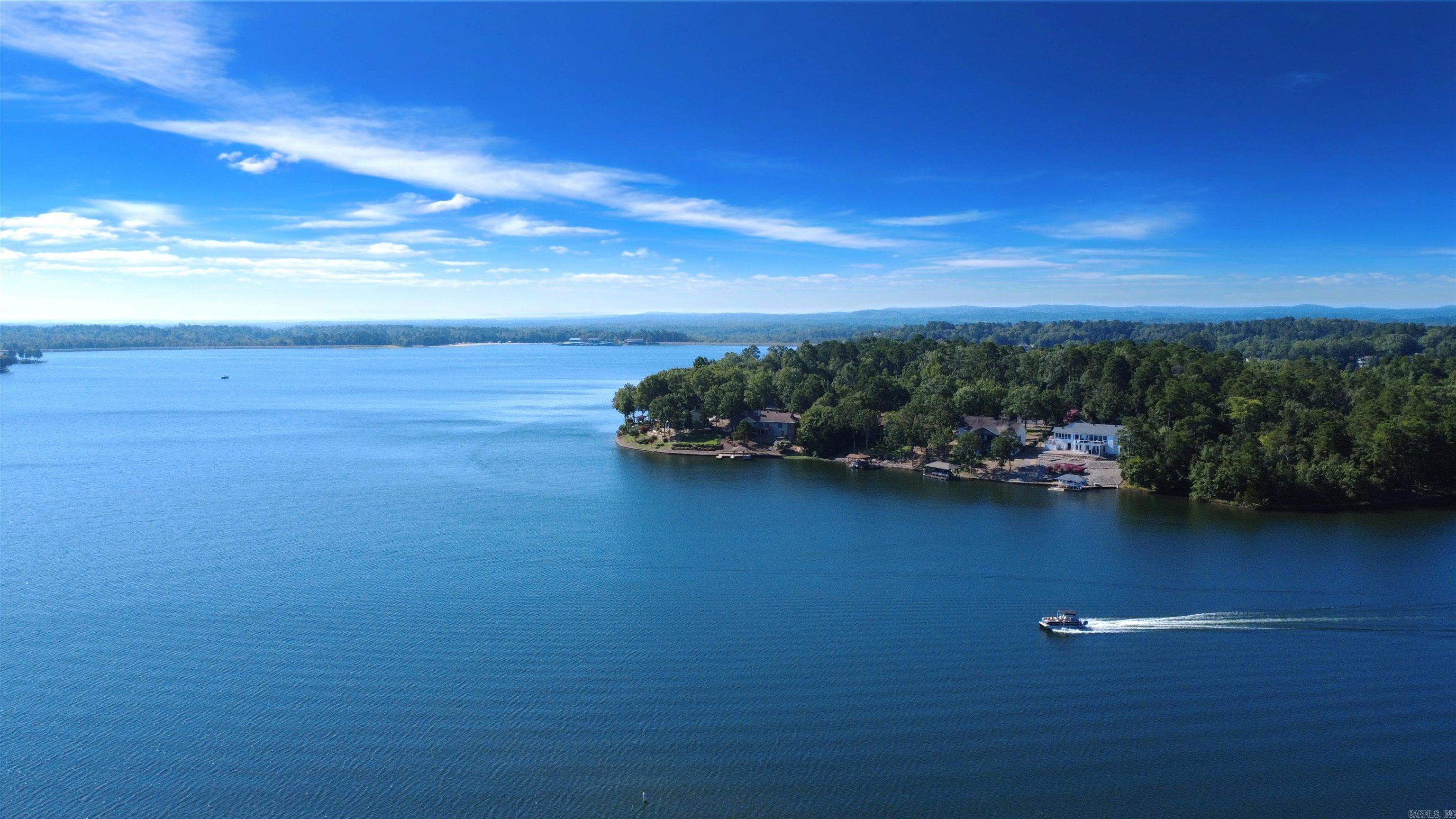 Experience Southern lakefront comfort in Hot Springs Village in this executive retreat on Lake Balboa, a 944-acre recreational lake. Positioned on a private .56-acre cul-de-sac lot with level circular drive, this polished two-level home offers 3,630 sq ft, 4 bedrooms, and 3.5 baths with three en-suites, ideal for multigenerational living, second home, or investment property. Fresh modern design showcases engineered wood flooring, dual electric fireplaces, and walls of windows in the Arkansas Room/office capturing serene water views. The well-appointed layout flows seamlessly to three expansive deck areas for elevated indoor-outdoor living. Enjoy peace of mind with a Generac® generator, smart lighting, smart locks, and security cameras. Offering immediate outdoor lake enjoyment, this listing conveys kayak launch, two sit-on-top kayaks, a Hobie paddleboard and the 20-foot Bayliner boat on the dock. The breezeway leads to the oversized garage that accommodates 2 cars plus golf cart/workshop with attic storage. Located in a premier gated golf and lake community with 11 lakes, 9 golf courses, marina, pickleball, trails, dining, and more. The ultimate turnkey lakeside opportunity.