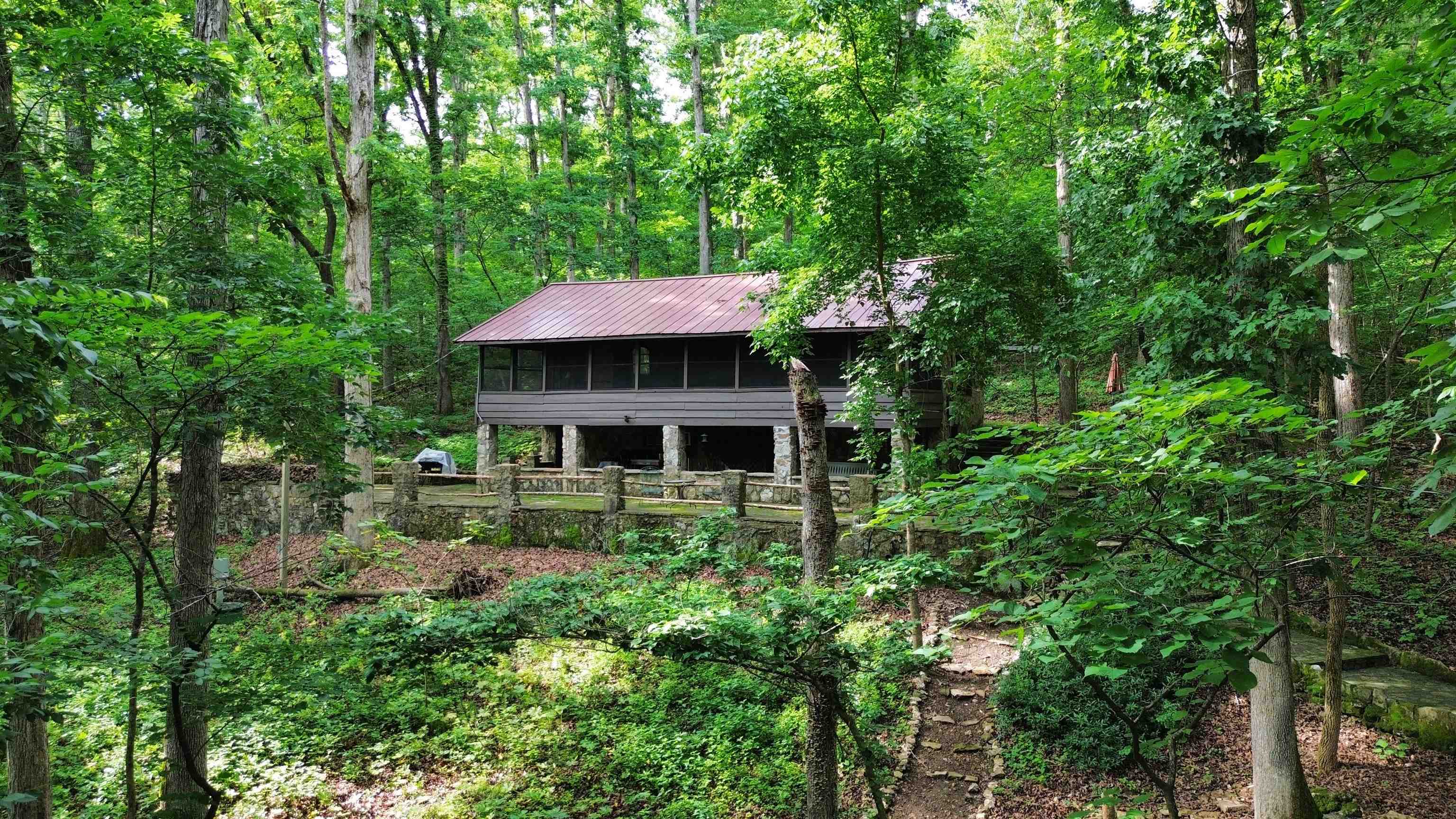 Unique 1937 cabin located in the Ozark Mountains on Historic Wahpeton Hill high above and just a short distance to Spring River, Loberg park, the river trails, the Hardy beach river access for swimming, kayaking, floating, world class fishing and downtown Old Hardy! 2 bed, 1.5 bath on 4.34 surveyed acres+/- in the depth of the woods yet minutes away from town amenities. Beautiful rock work all around the home, sit and relax outside while enjoying the fruits of nature. Main level includes living area, 2 bedrooms, large screened in porch, and a warming fireplace. Downstairs includes kitchen, full bath and half bath. Check out the history of this one of a kind property. Includes new roof 2022, new windows 2024, new insulation 2024.