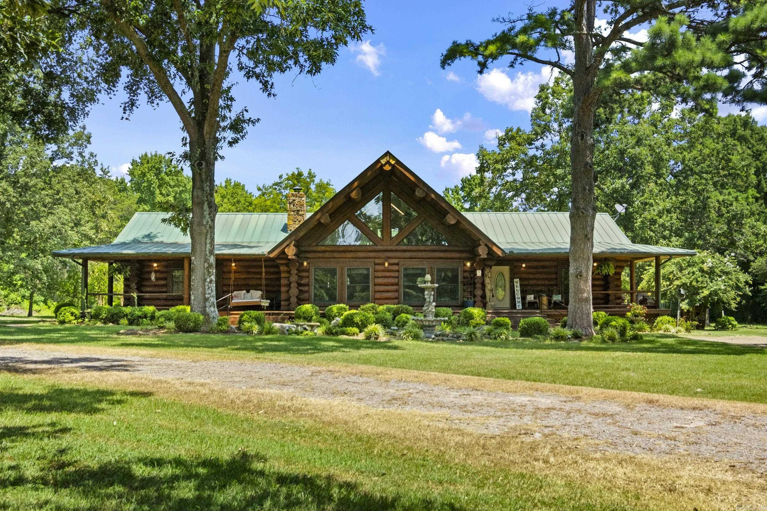 Stunning 3,189 sq. ft. custom log home on 9.62 beautiful acres, constructed from Engelmann Spruce grown in Canada and originally crafted in Colorado. The logs were carefully relocated and professionally assembled on site, offering timeless appeal and exceptional craftsmanship. The main living area features vaulted ceilings, exposed log beams, natural wood finishes, and a massive stone fireplace plumbed for propane or wood burning. The home offers 3 bedrooms plus a spacious loft with built-in closets, ideal as a 4th bedroom or office, 2 full baths, and 1 half bath. The kitchen has been updated in recent years with granite countertops and ss appliances and includes a storm shelter under the stairs. A wraparound porch spans approximately three-quarters of the home, overlooking a private pond and peaceful acreage. Enjoy abundant wildlife, a private drive, large deck, above-ground pool, and ample storage. The oversized heated/cooled 2-car garage includes two storage rooms and has previously been used as an entertaining space. This exceptional property offers privacy, natural beauty, and a tranquil lifestyle. Mineral rights negotiable with acceptable offer.